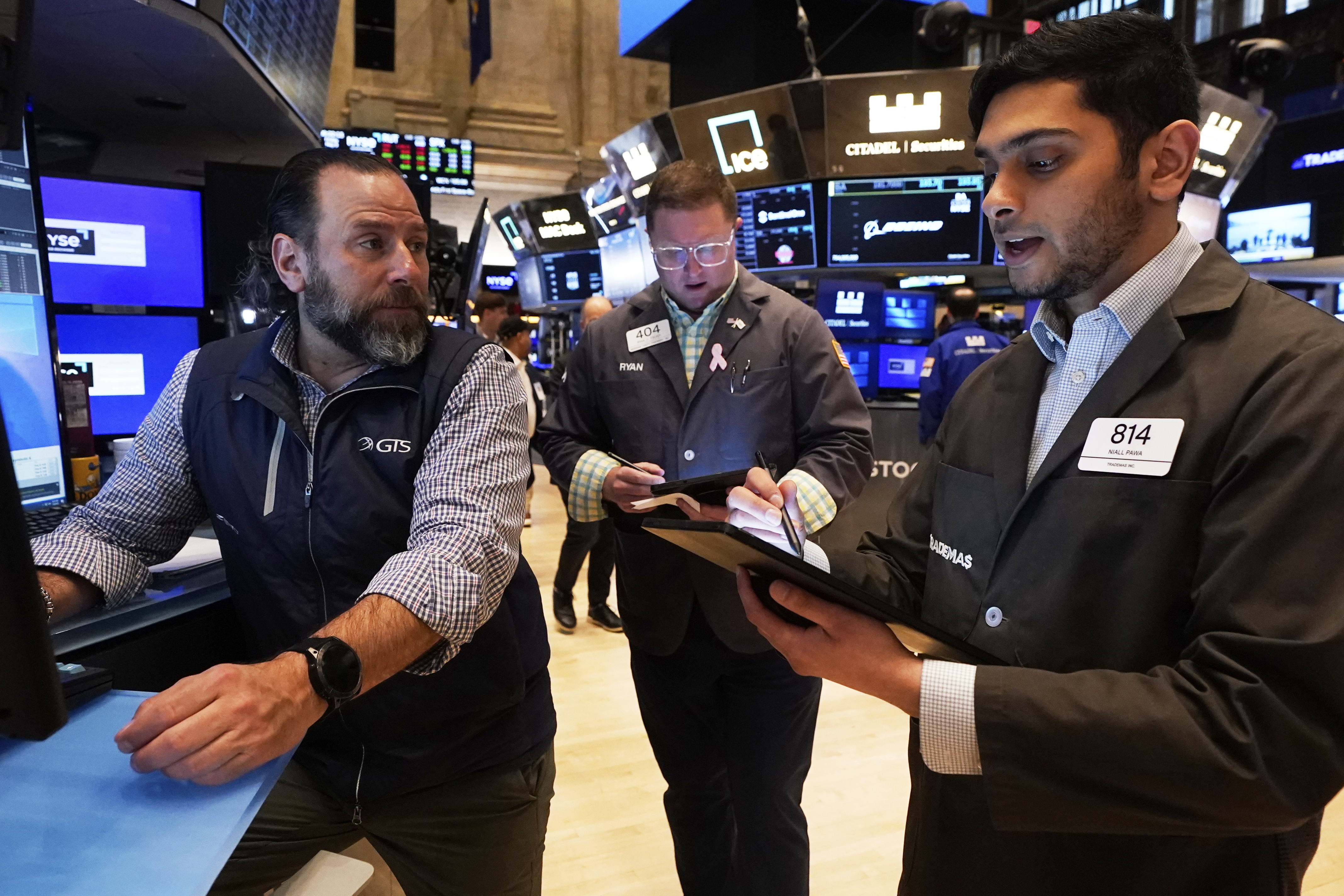 Specialist Michael Pistillo, left, works with traders Ryan Falvey, center, and Niall Pawa on the floor of the New York Stock Exchange, Friday, May 9, 2025. (AP Photo/Richard Drew)