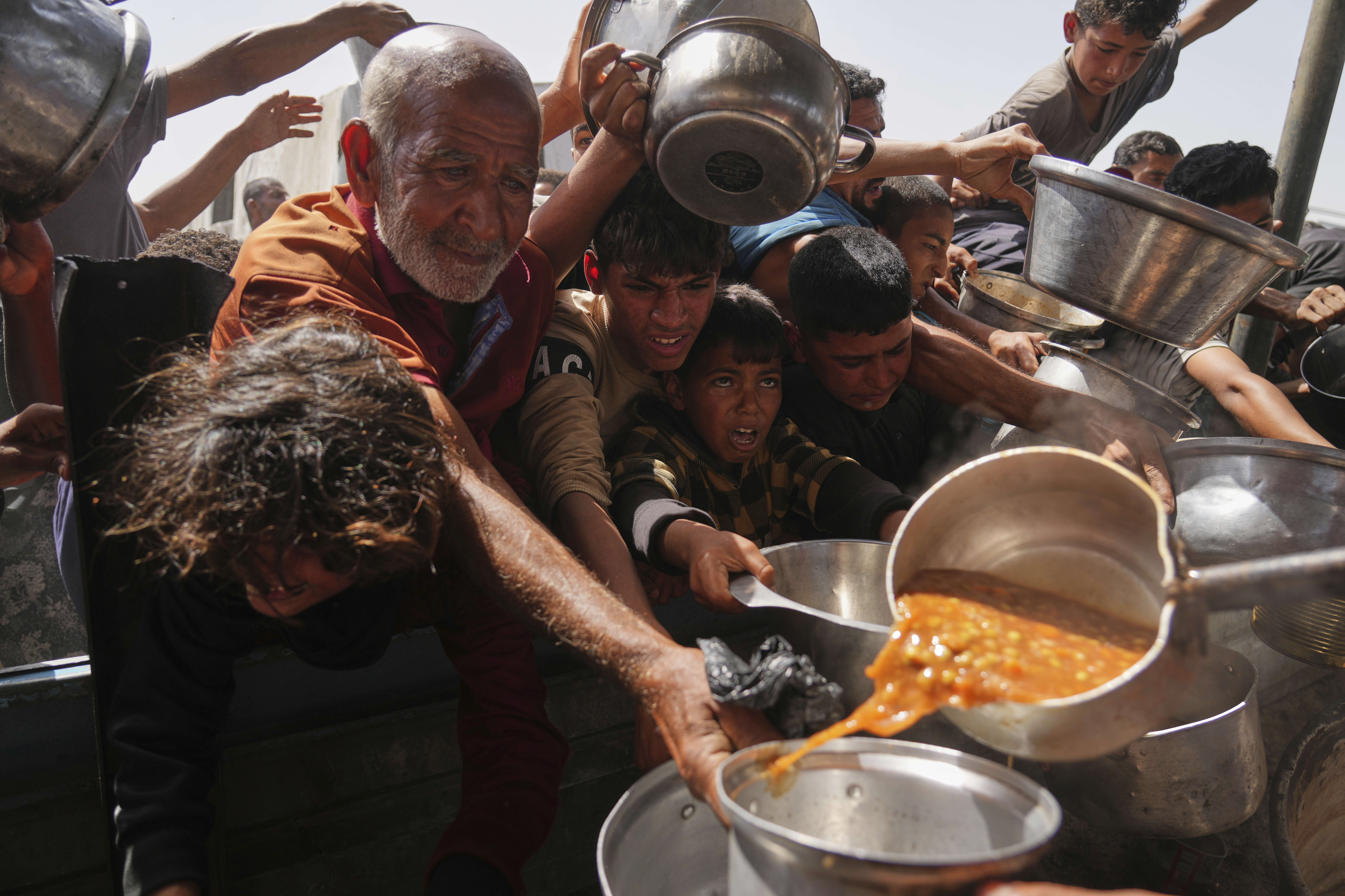 Palestinians struggle to get donated food at a community kitchen in Khan Younis, Gaza Strip, Sunday, May 11, 2025. (AP Photo/Abdel Kareem Hana)