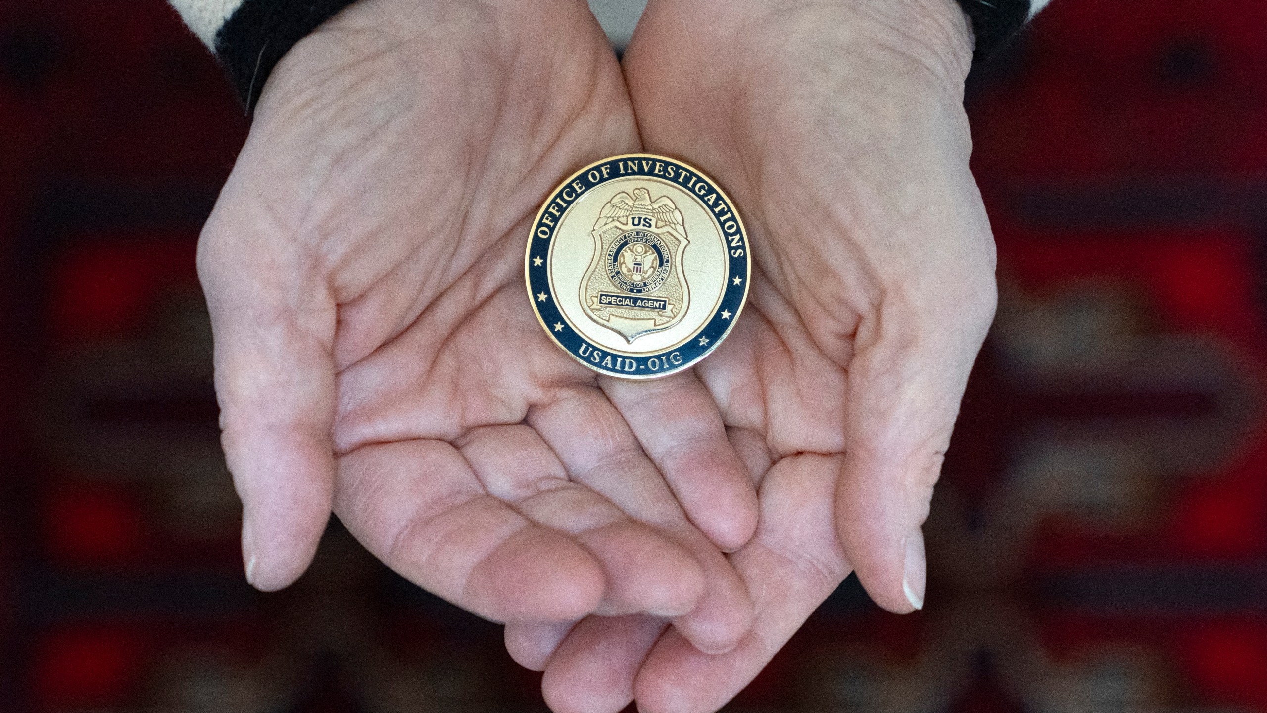Cathy Votaw, 69, holds a coin from the USAID Office of Investigations, Thursday, Feb. 27, 2025, in Washington. (AP Photo/Jacquelyn Martin)