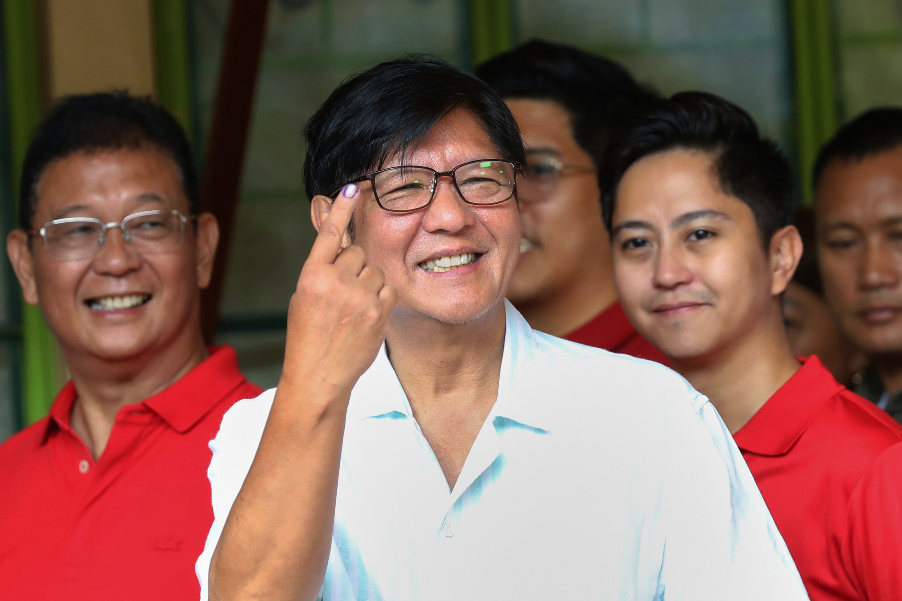 In this photo provided by the Presidential Communications Office, Philippines' President Ferdinand Marcos Jr., center, shows the indelible ink on his finger after casting his ballot at a polling station in Batac City, Ilocos Norte province, Philippines, Monday, May 12, 2025. (Presidential Communications Office via AP)