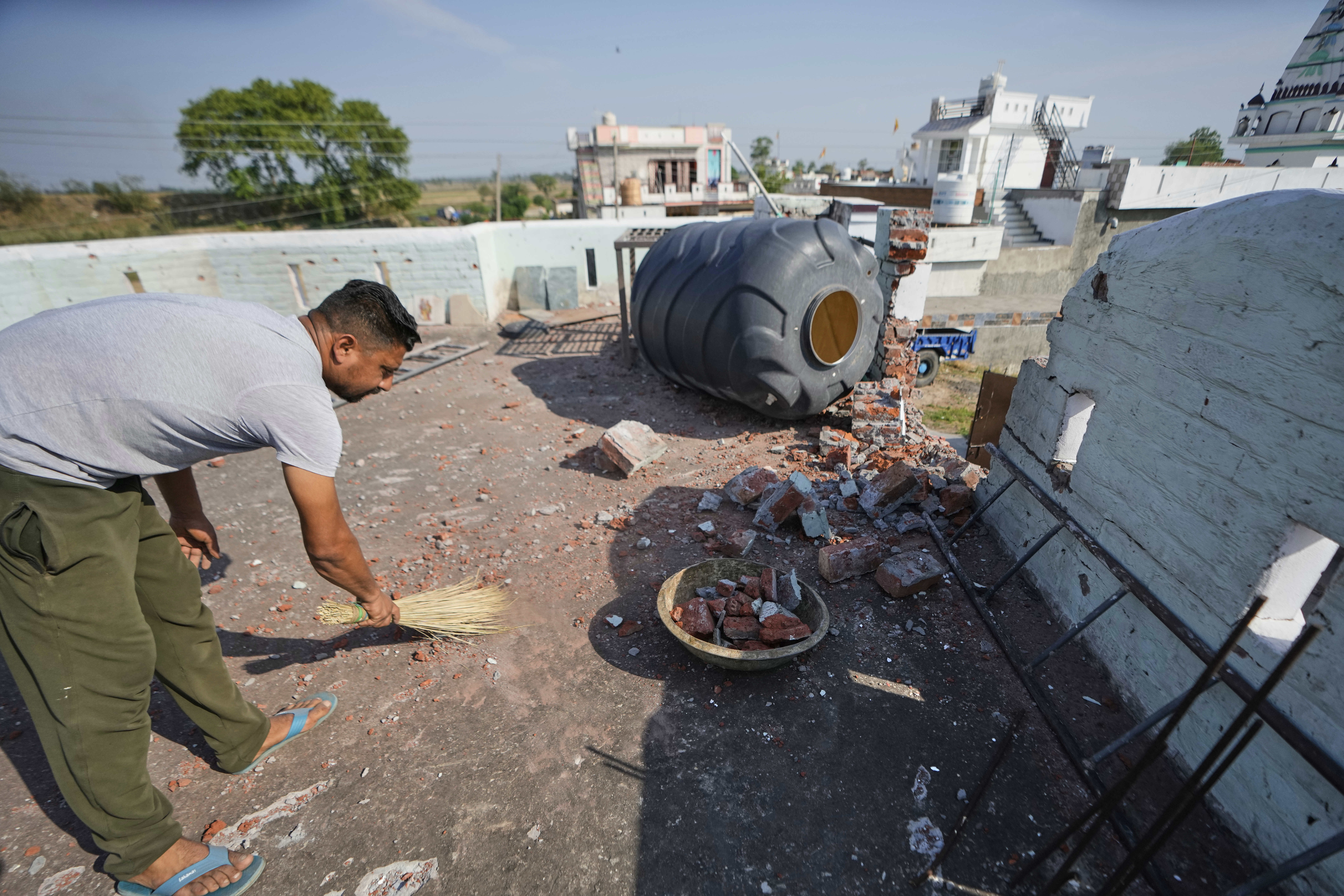 A villager cleans the roof of his house damaged by Pakistani artillery shelling at RS Pura, along the International Border, India, Monday, May 12, 2025, after the two countries reported no incidents of firing overnight. (AP Photo/Channi Anand)
