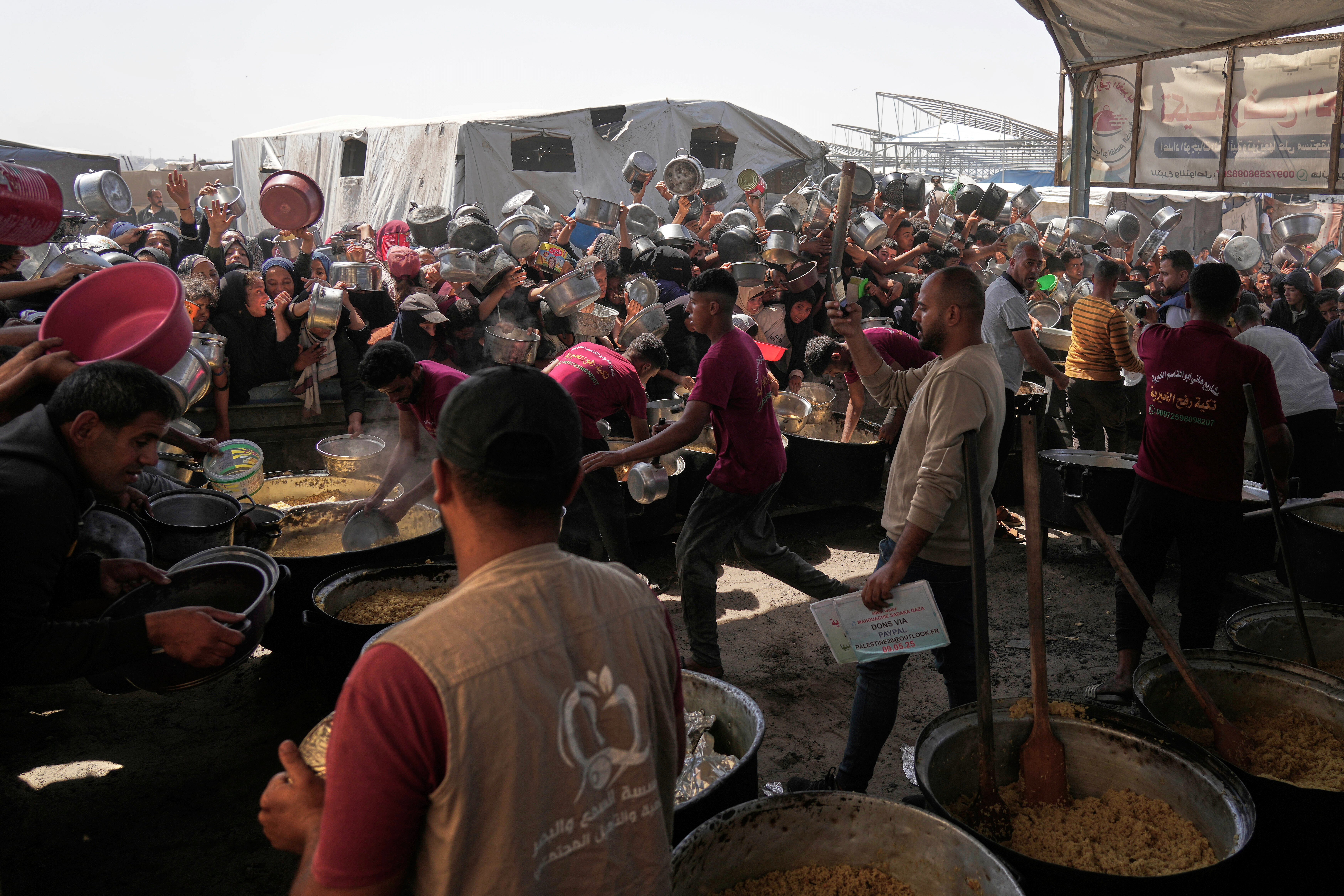 Palestinians struggle to obtain donated food at a community kitchen in Khan Younis, in the southern Gaza Strip, Friday, May 9, 2025. (AP Photo/Abdel Kareem Hana)