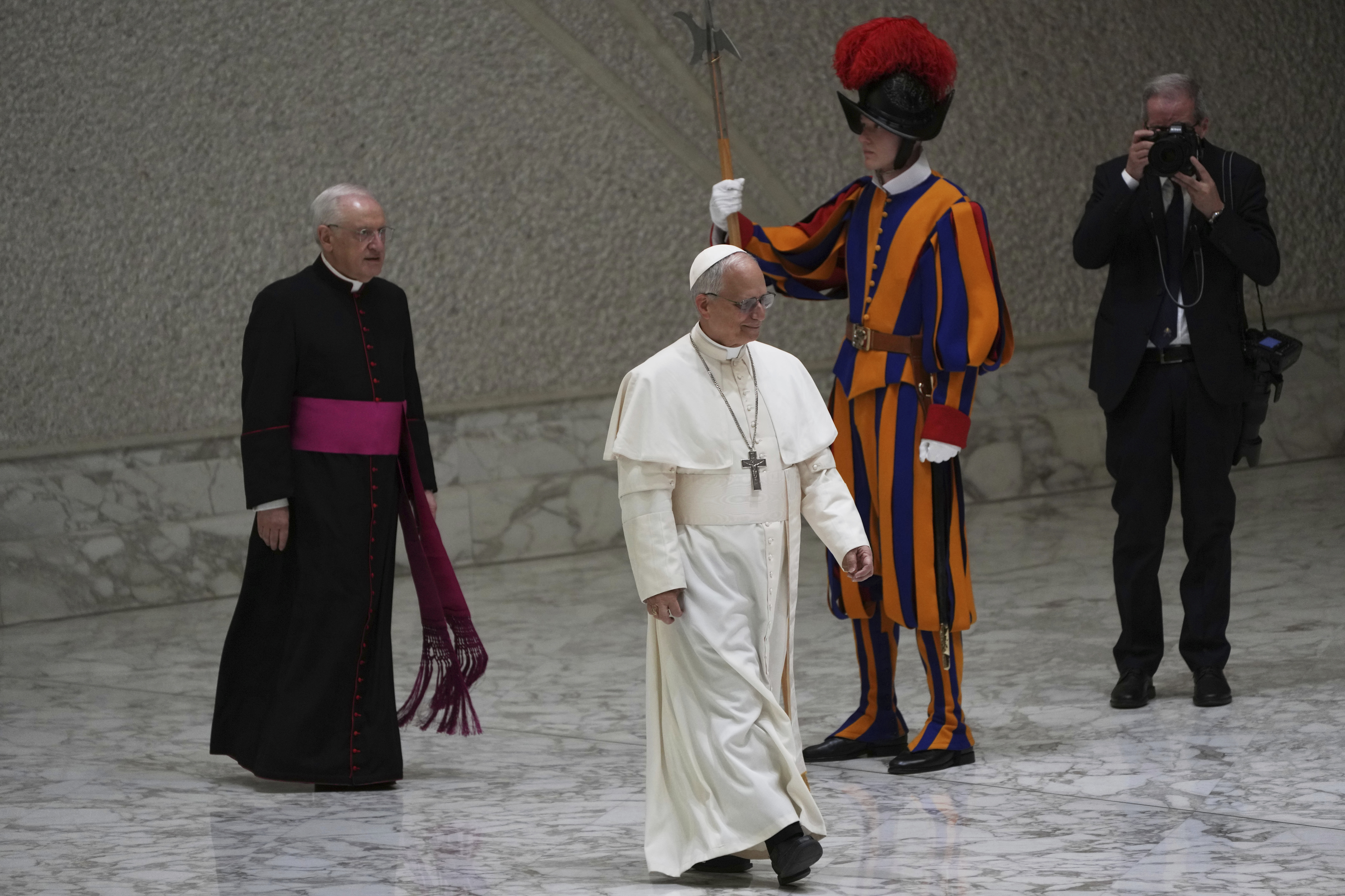 Pope Leo XIV, followed by the caretaker of the Papal Household, Bishop Leonardo Sapienza, arrives to meet with members of the international media in the Paul VI Hall at the Vatican, Monday, May 12, 2025. (AP Photo/Domenico Stinellis)