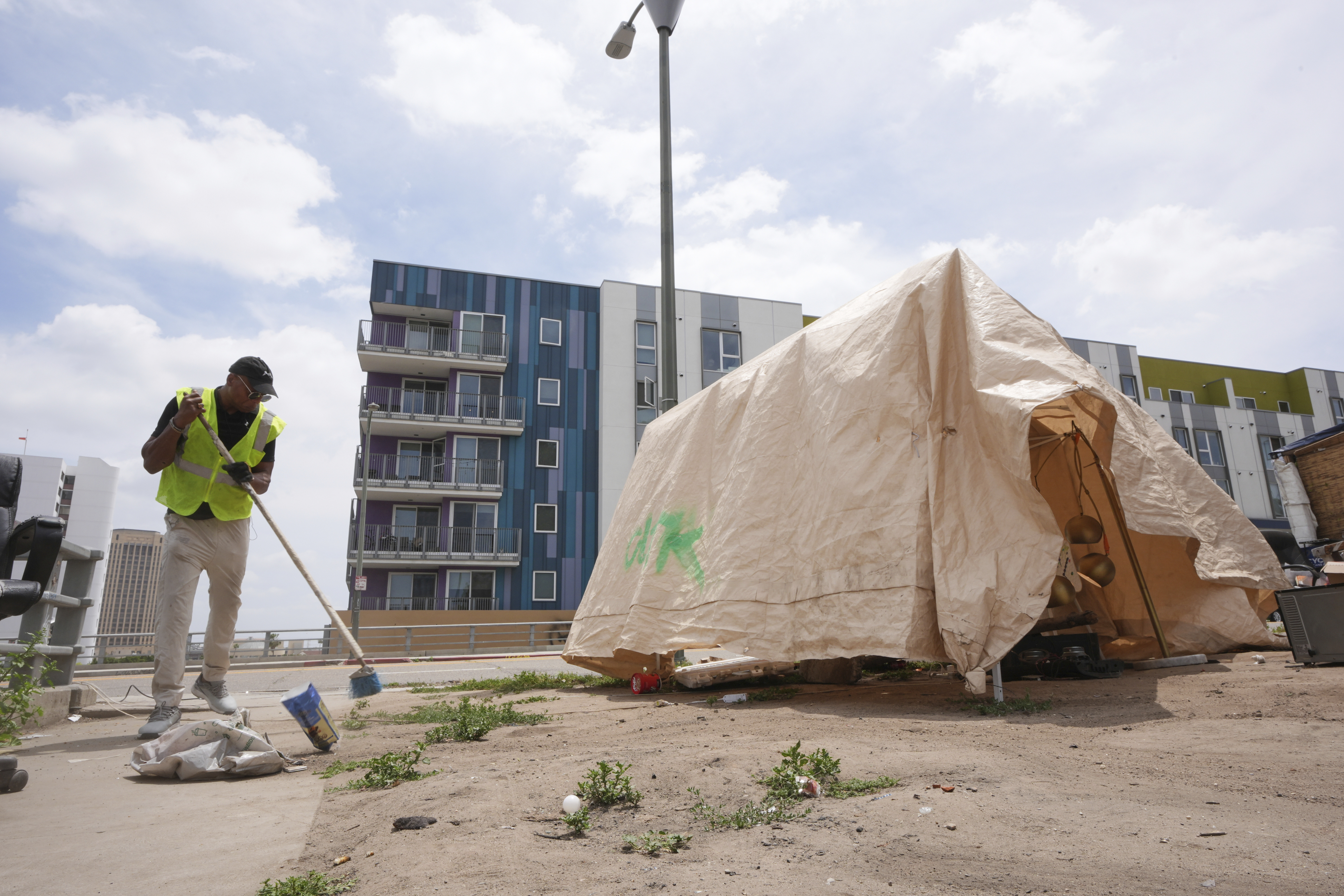 Jay Joshua cleans up around a homeless encampment where he currently lives, Monday, May 12, 2025, in Los Angeles. (AP Photo/Damian Dovarganes)