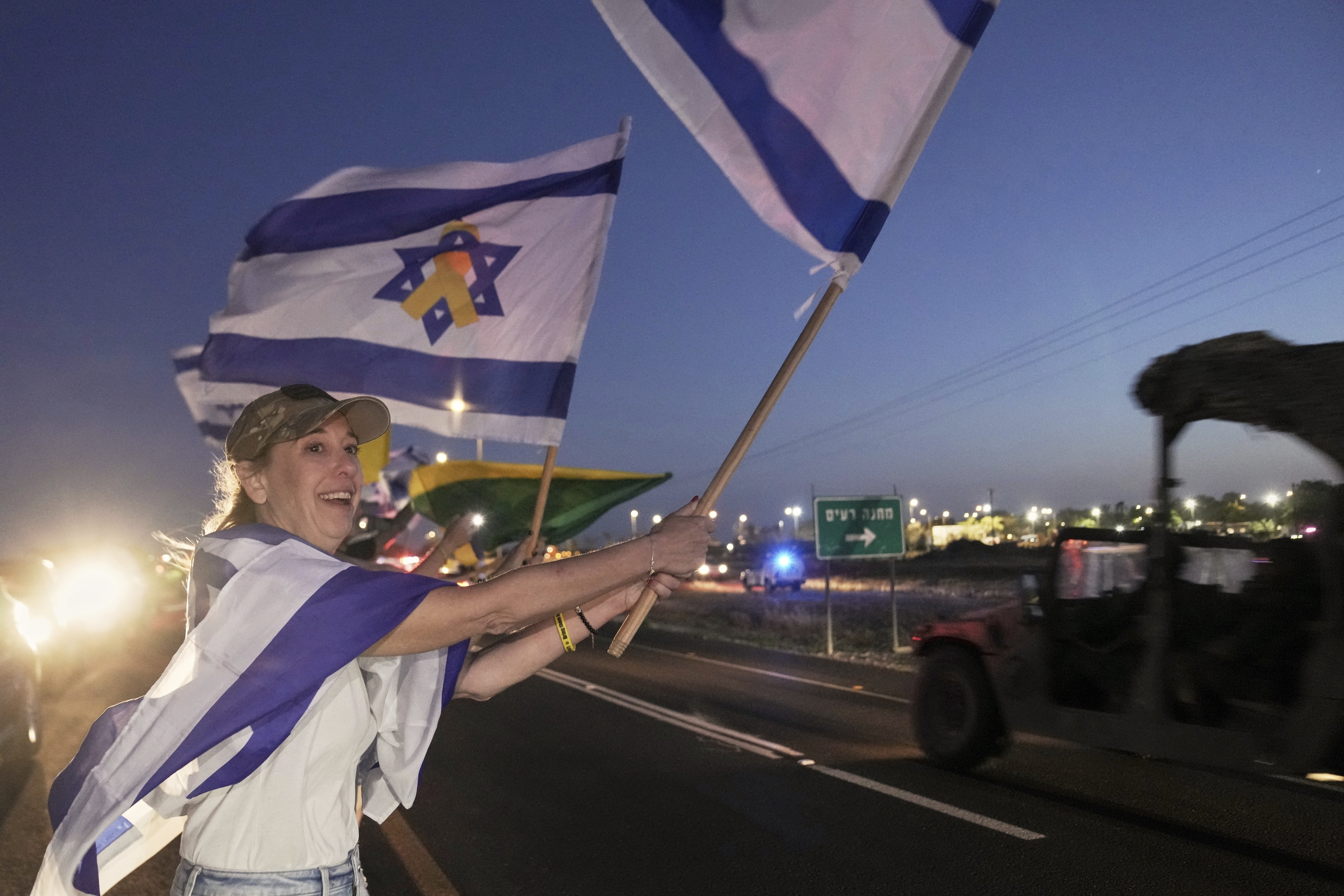 Amy Lieberman from Hillsdale, New Jersey, foreground, joins Israelis waving flags as the convoy carrying freed Israeli-American soldier Edan Alexander arrives after his release from Hamas captivity in Gaza to an army base in Reim, near the Gaza border, southern Israel, Monday, May 12, 2025.(AP Photo/Maya Alleruzzo)
