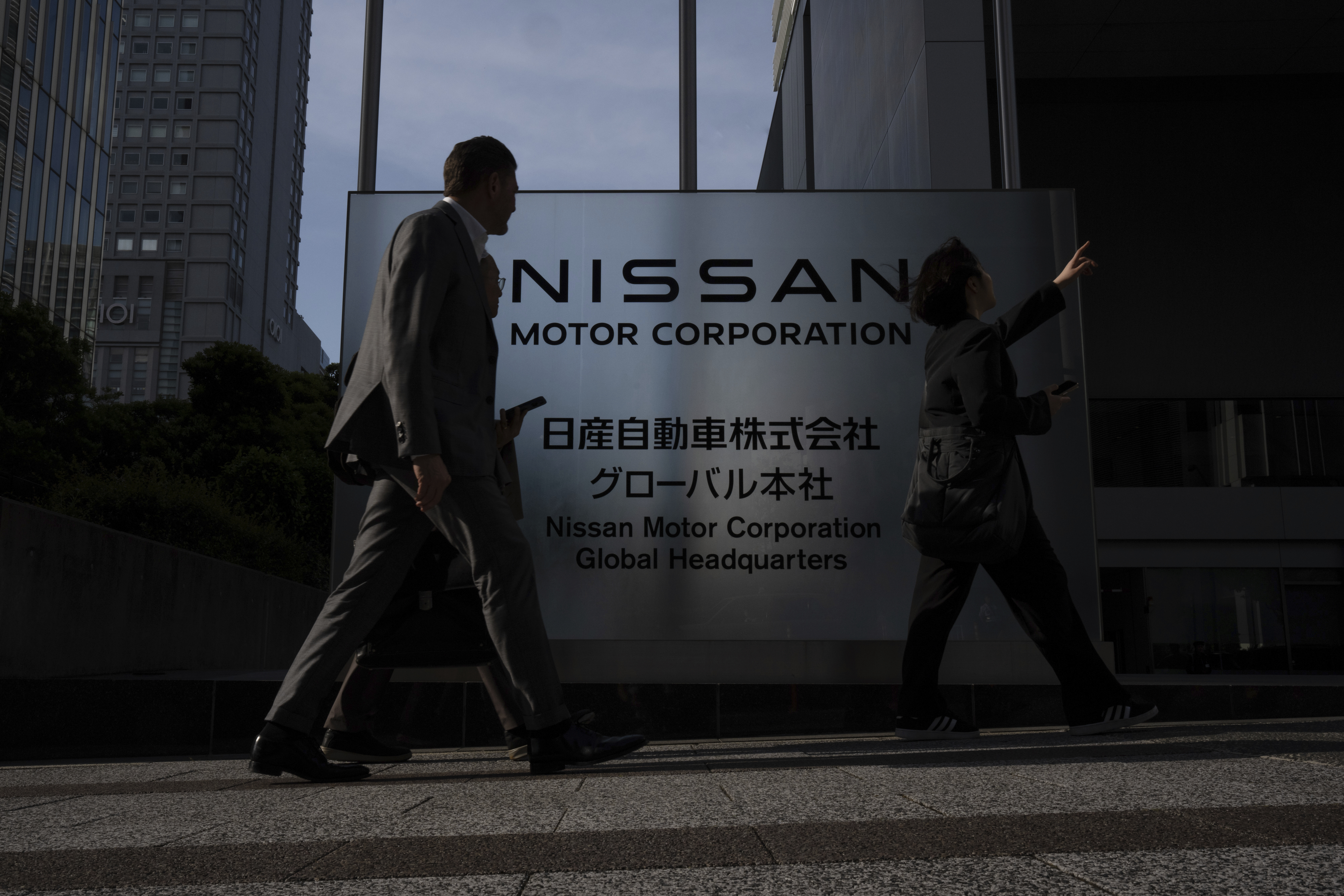 Visitors walk past Nissan signage at Nissan headquarters in Yokohama, Tuesday, May 13, 2025. (AP Photo/Louise Delmotte)