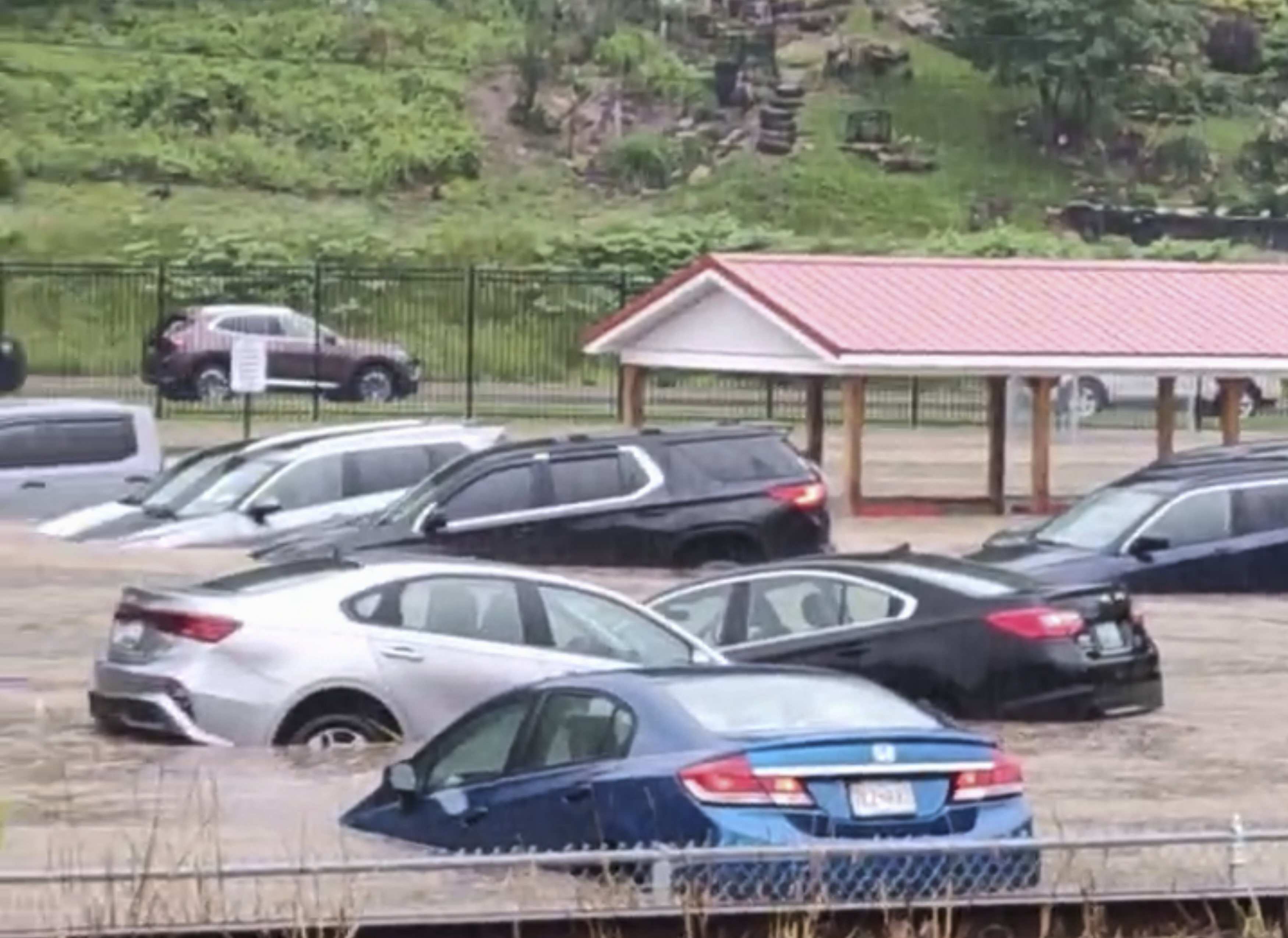 Cars are submerged in a parking lot of Westernport Elementary School as flooding forces the evacuation of the school, and downtown homes and businesses were inundated with rising floodwaters in rural Westernport, Md., Tuesday, May 13, 2025. (Aaron Stallings via AP)