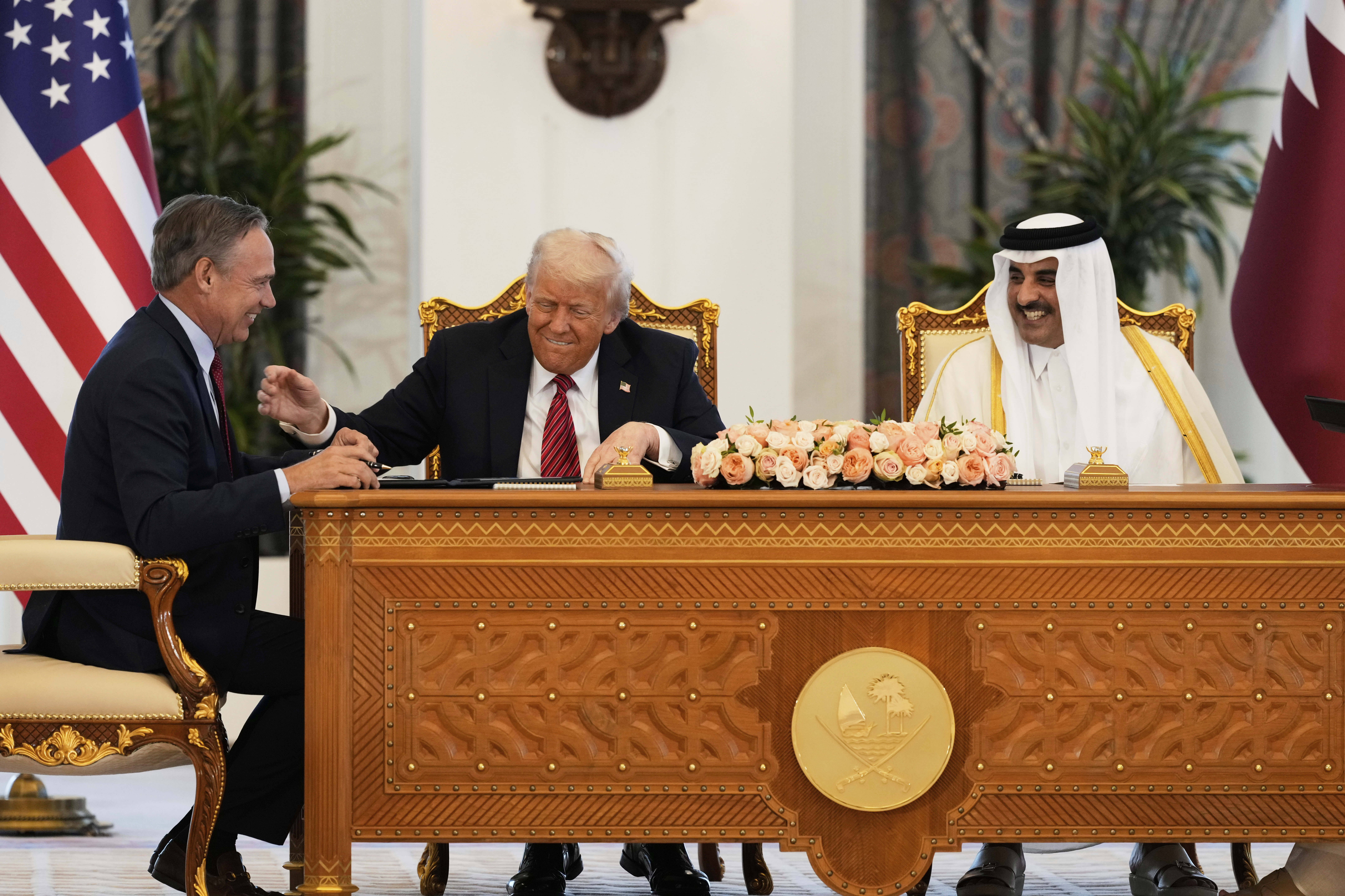 President Donald Trump, center, Qatar's Emir Sheikh Tamim bin Hamad Al Thani and Kelly Ortberg, President and Chief Executive Officer, The Boeing Company, left, share a moment during a signing ceremony at the Amiri Diwan in Doha, Qatar, Wednesday, May 14, 2025. (AP Photo/Alex Brandon)
