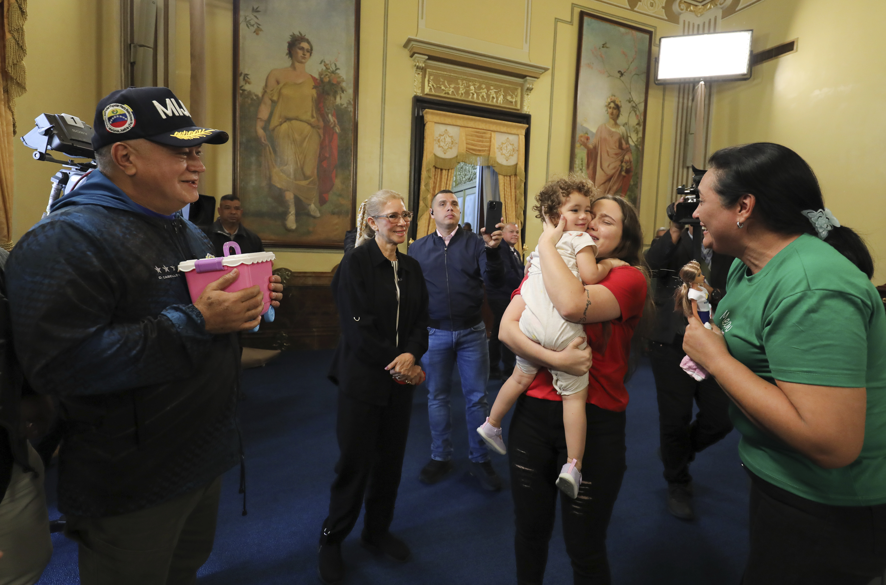 In this photo released by the Miraflores press office, first lady Cilia Flores, second from left, and Interior Minister Diosdado Cabello, left, watch as 2-year-old Maikelys Espinoza is reunited with her mother Yorely Escarleth Bernal Inciarte at Miraflores presidential palace in Caracas, Venezuela, Wednesday, May 14, 2025. The U.S. deported Bernal to Venezuela on April 25 and sent the child's father to a maximum-security prison in El Salvador in March. (Zurimar Campos/Miraflores press office via AP)