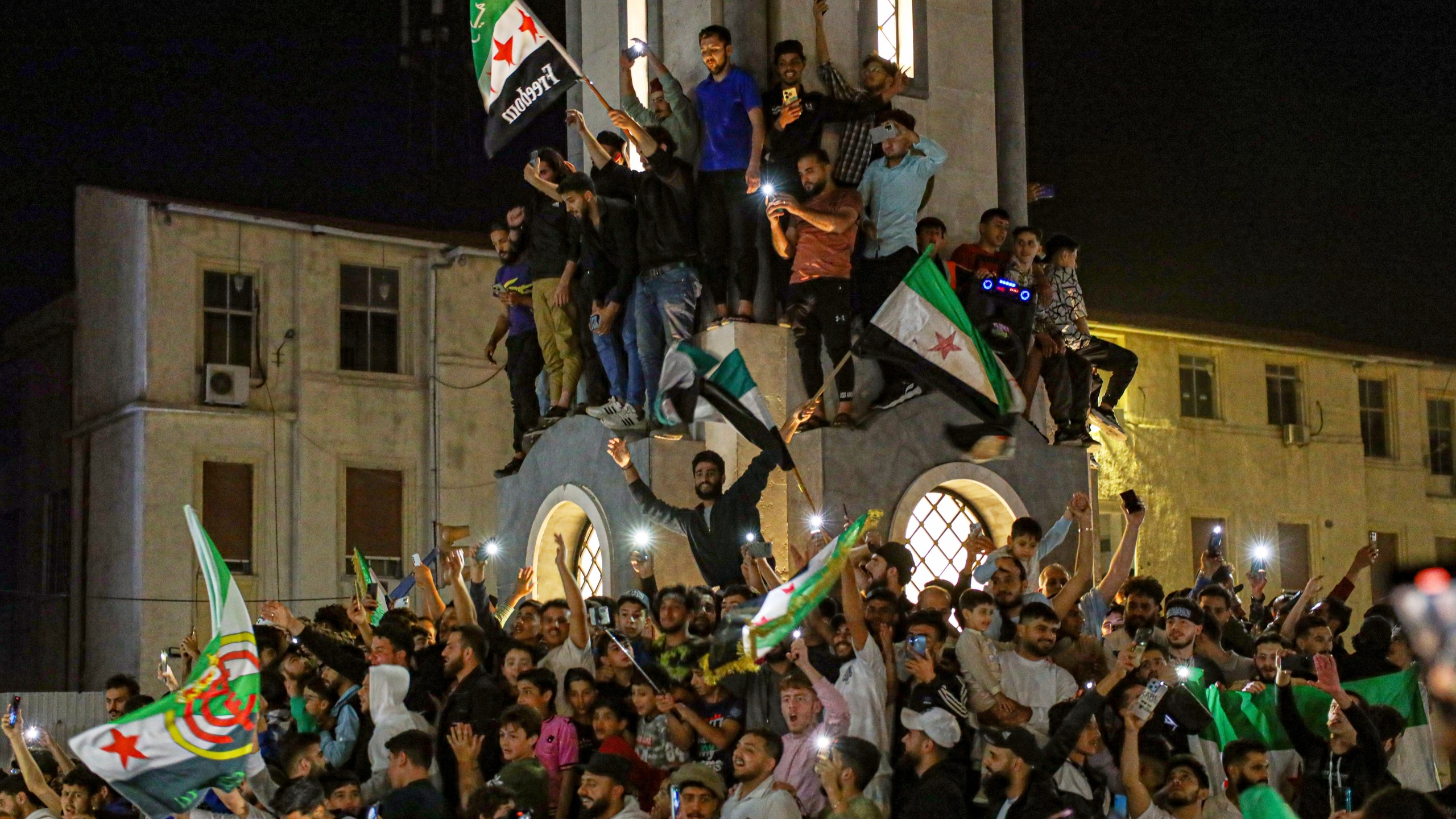 Syrians celebrate after U.S. President Donald Trump announced plans during his visit to Saudi Arabia to ease sanctions on Syria and normalize relations with its new government, in Homs, Syria, late Tuesday, May 13, 2025.(AP Photo/Omar Albam)