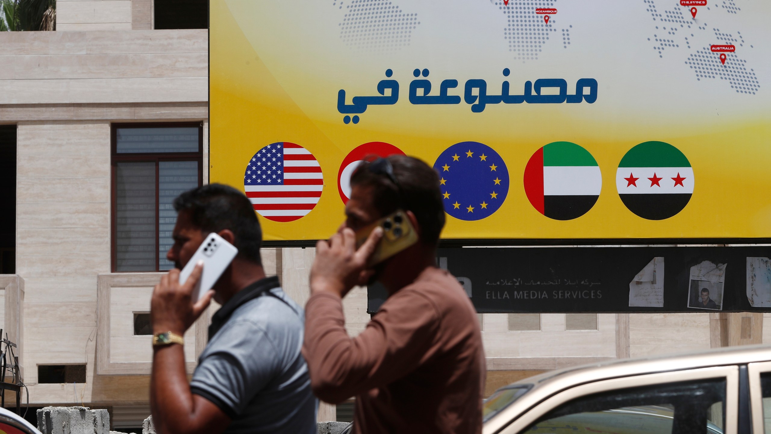 Syrian men speak on their phones on a street in Damascus, Syria, Wednesday, May 14, 2025. (AP Photo/Omar Sanadiki)