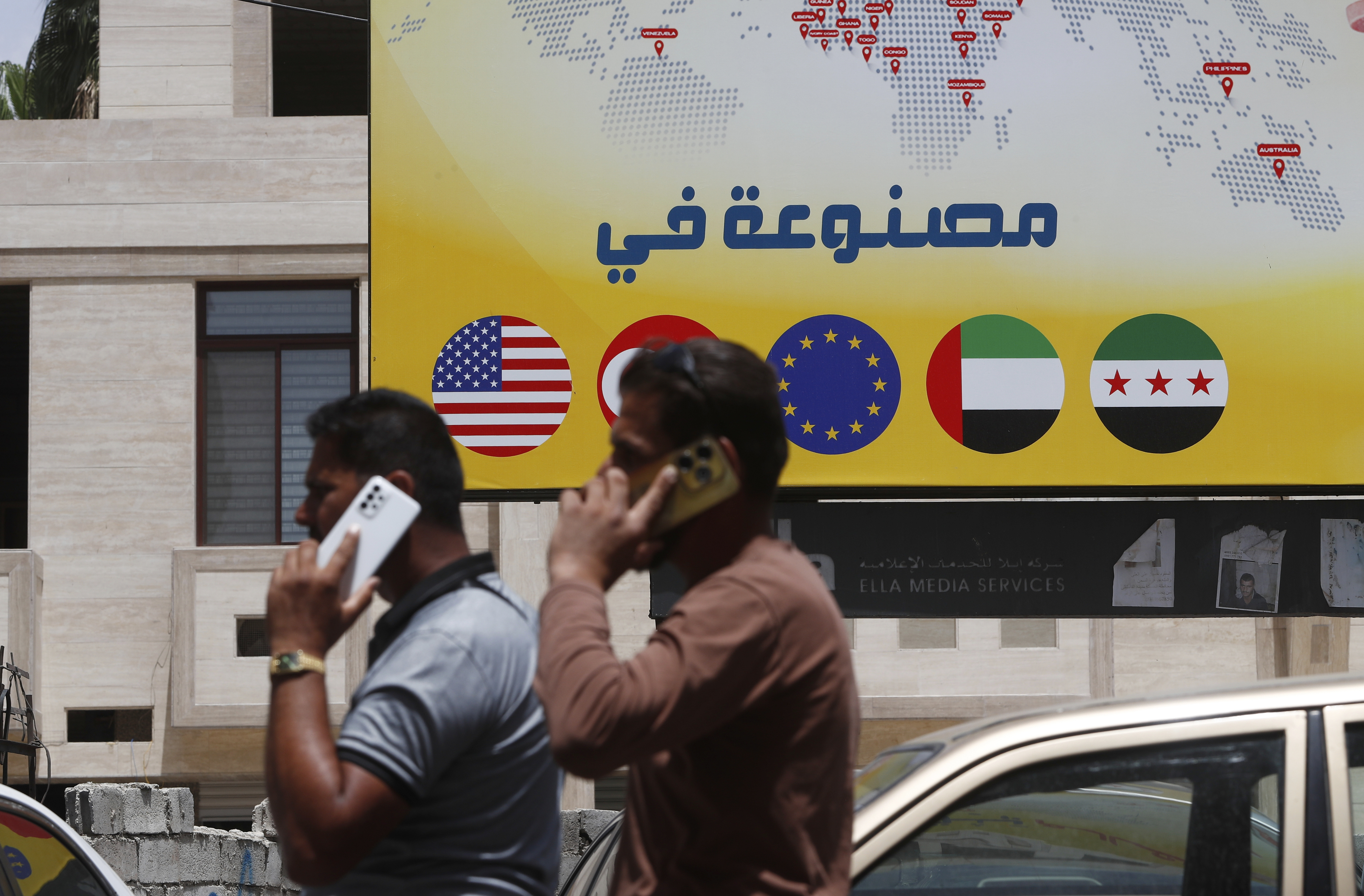 Syrian men speak on their phones on a street in Damascus, Syria, Wednesday, May 14, 2025. (AP Photo/Omar Sanadiki)