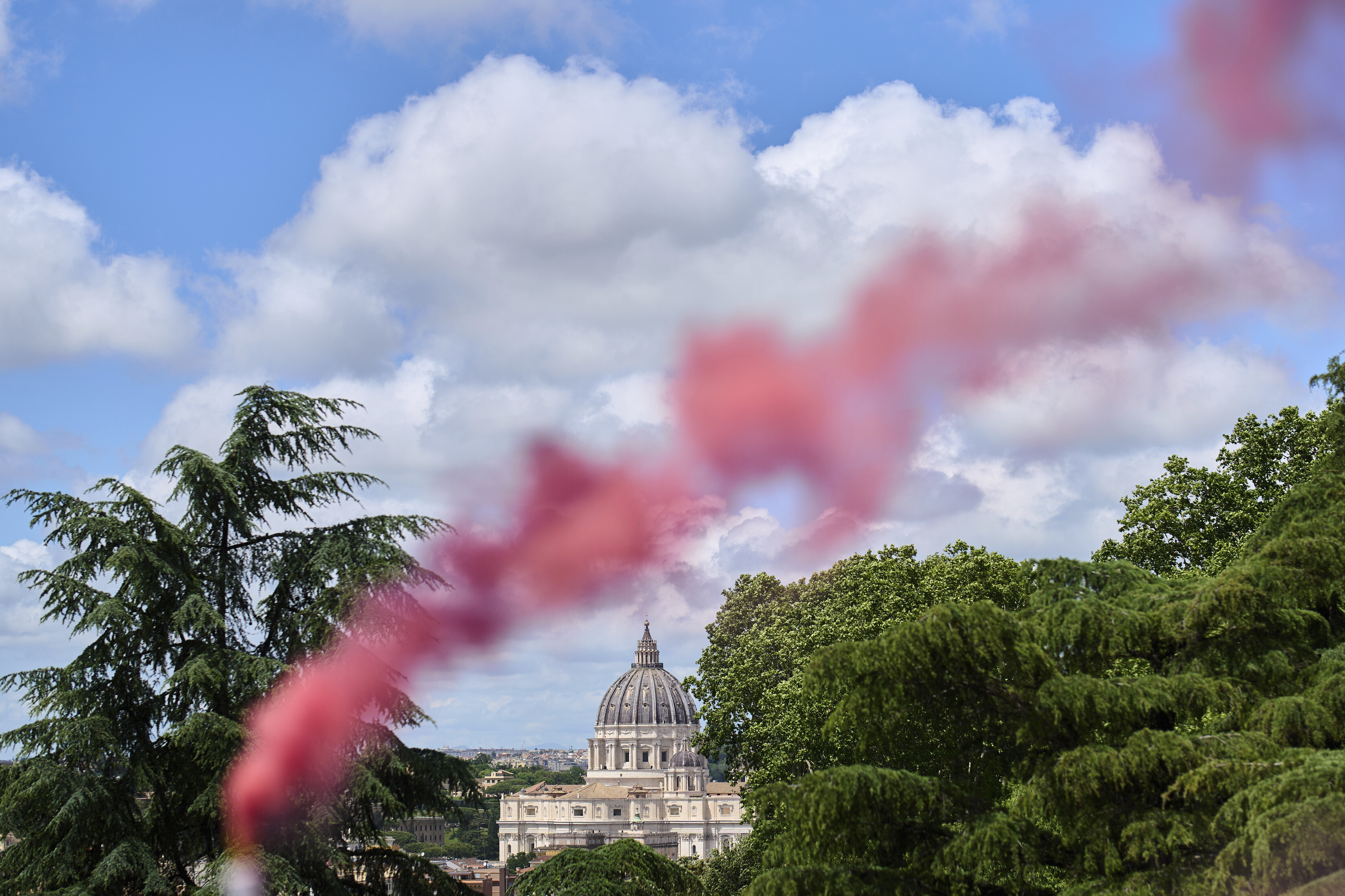 FILE - Pink smoke rises in front of St. Peter's Basilica during a protest by the Women's Ordination Conference calling for full equality for women in the Catholic Church on the first day of the conclave to elect the 267th pope in Rome on Wednesday, May 7, 2025. (AP Photo/Bernat Armangue, File)