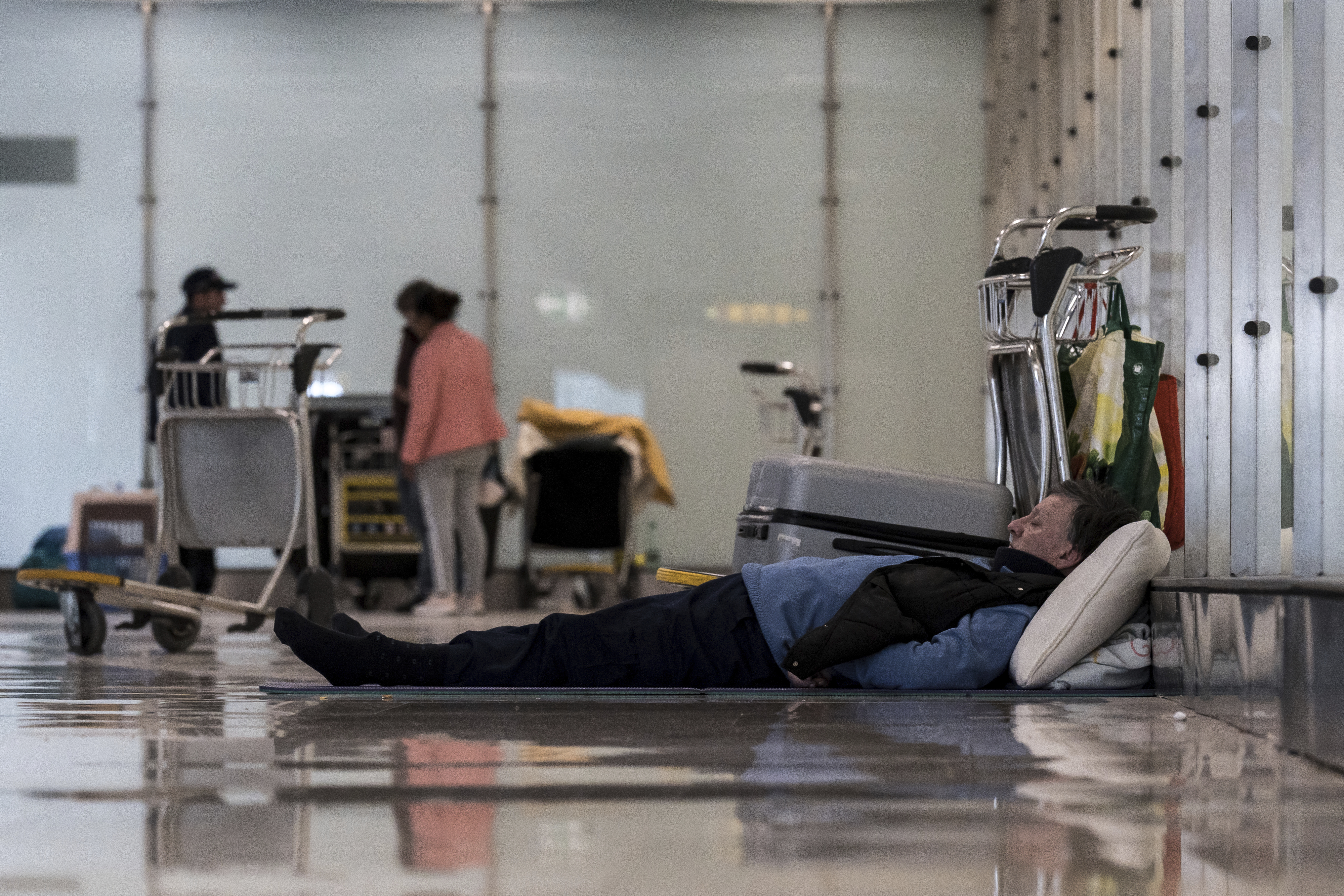 A person sleeps on the floor of Terminal 4 at Adolfo Suárez-Madrid Barajas Airport in Madrid, Spain, Monday, May 12, 2025. (Diego Radames/Europa Press via AP)