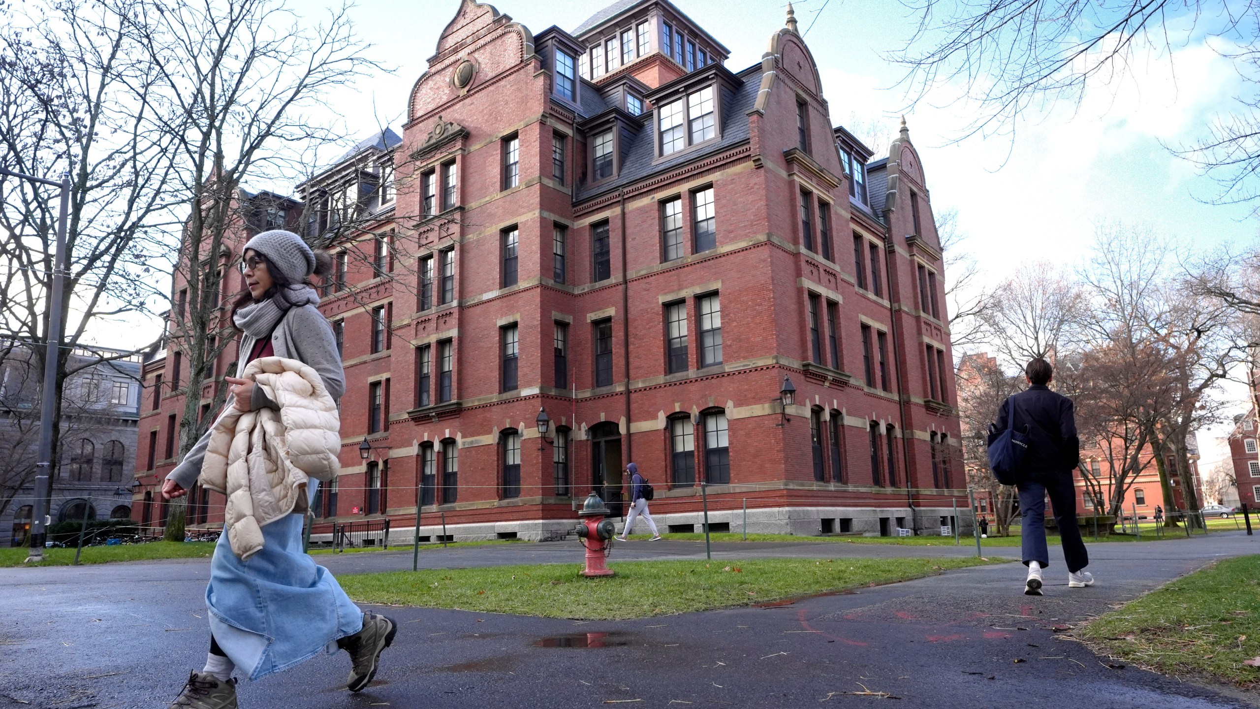 FILE - People walk between buildings, Dec. 17, 2024, on the campus of Harvard University in Cambridge, Mass. (AP Photo/Steven Senne, File)