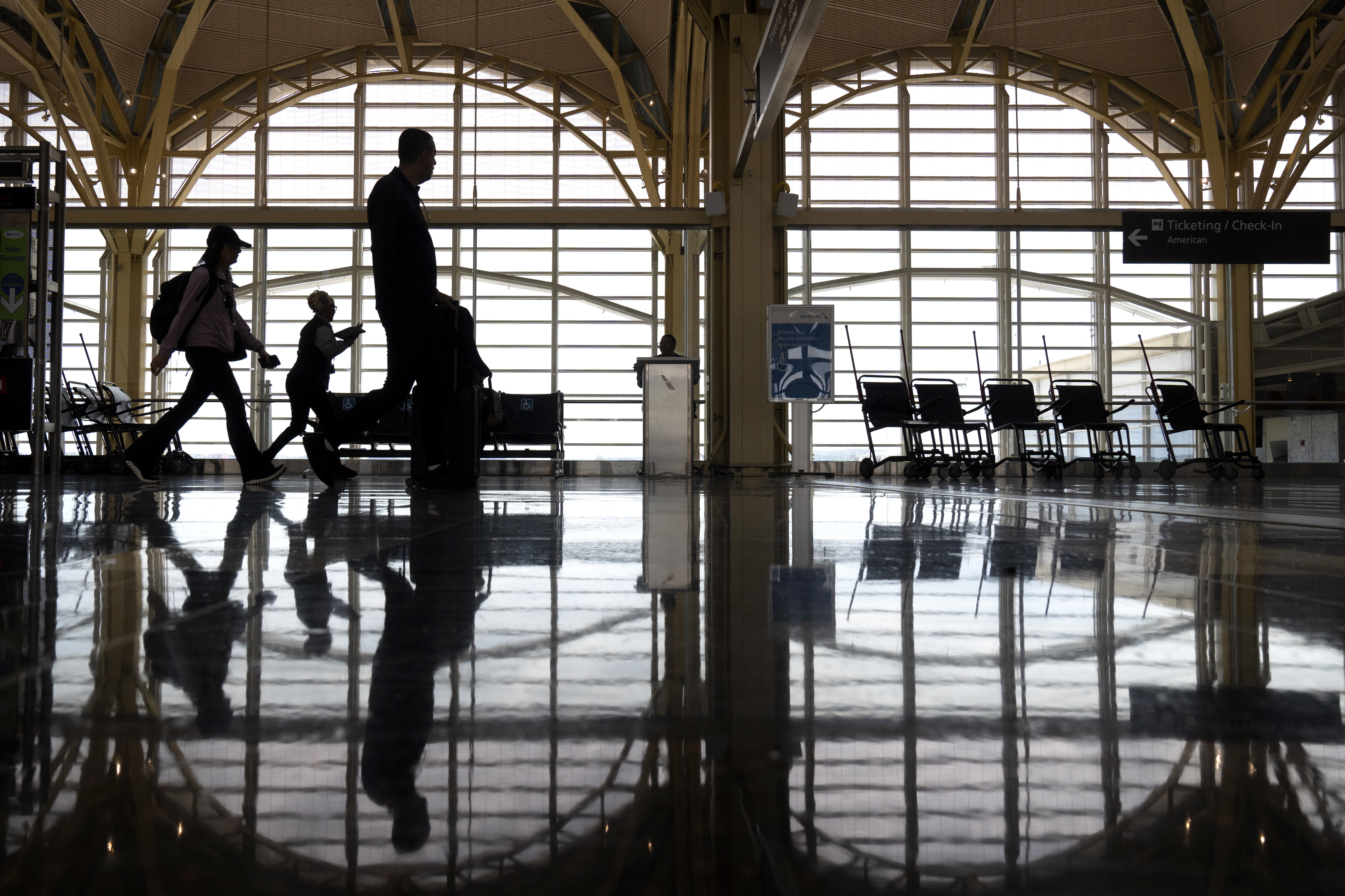 FILE - Travelers walk along a concourse at Reagan National Airport on July 19, 2024, in Arlington, Va. (AP Photo/Mark Schiefelbein, file)