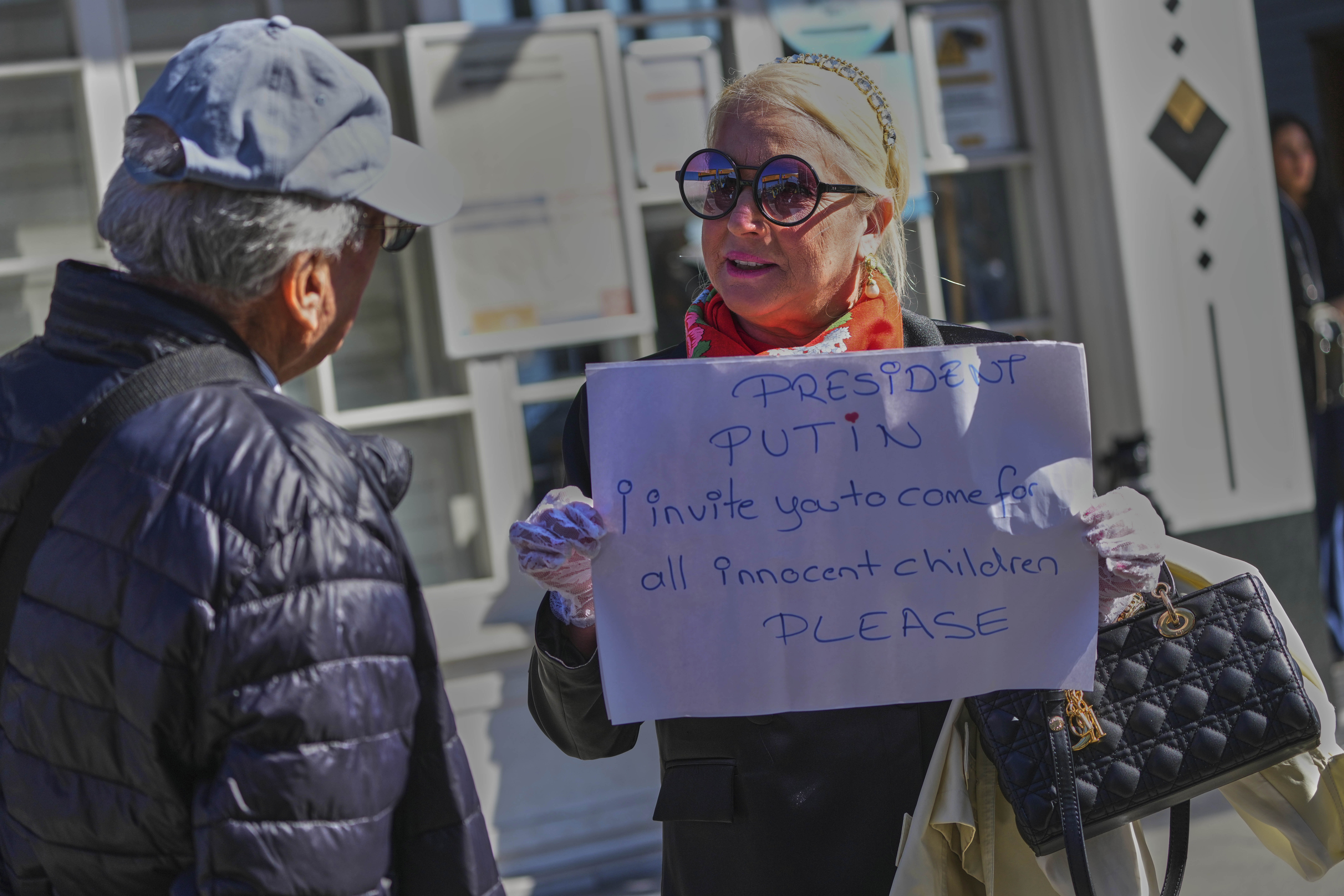 Ayse Sahil, whose family emigrated from Bolshevik in Russia, holds a board near Dolmabahce palace where talks between Russian and Ukrainian delegations are expected, in Istanbul, Turkey, Thursday, May 15, 2025. (AP Photo/Dilara Acikgoz)