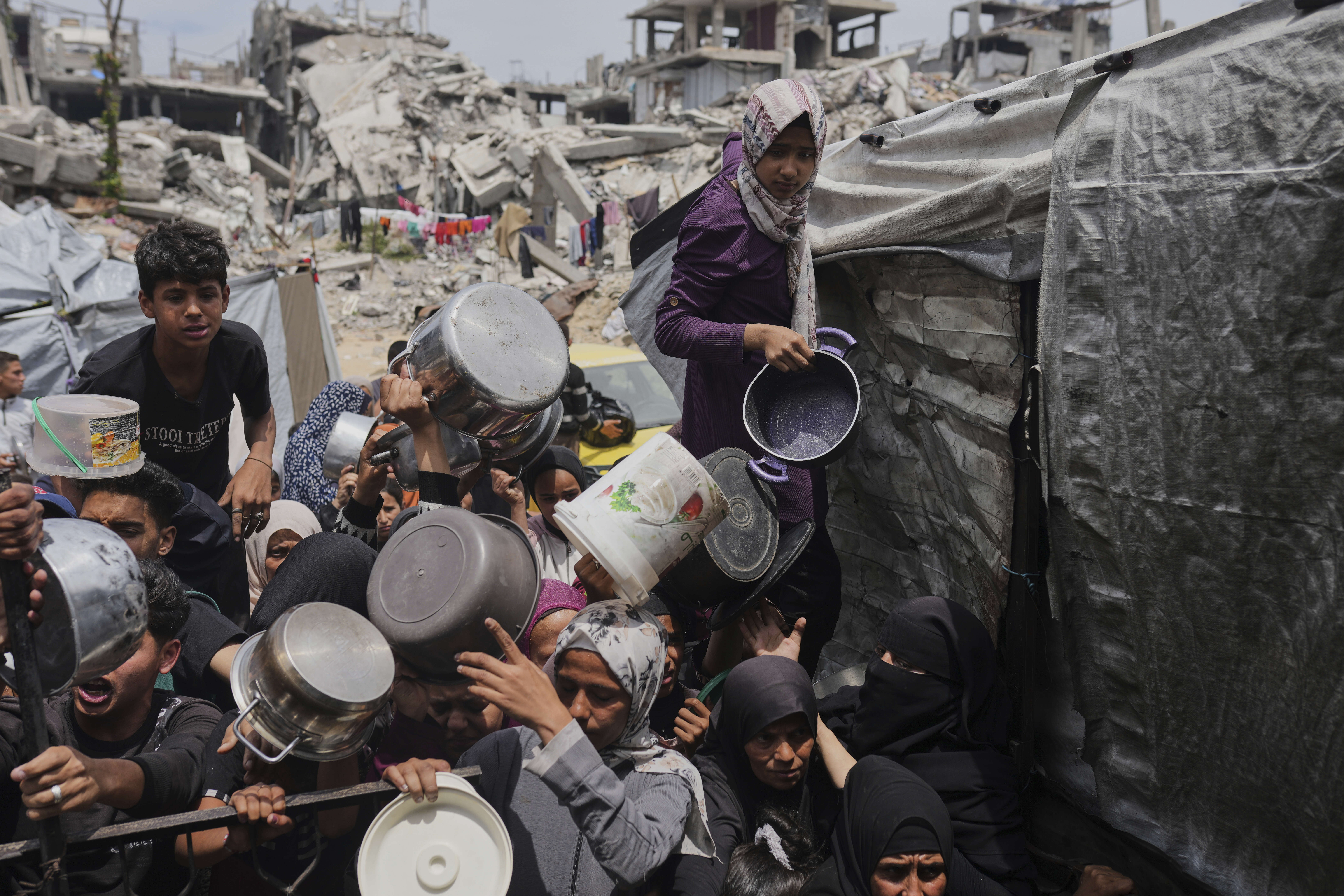 Palestinians struggle to get donated food at a community kitchen in Jabalia, northern Gaza Strip, Thursday, May 15, 2025. (AP Photo/Jehad Alshrafi)