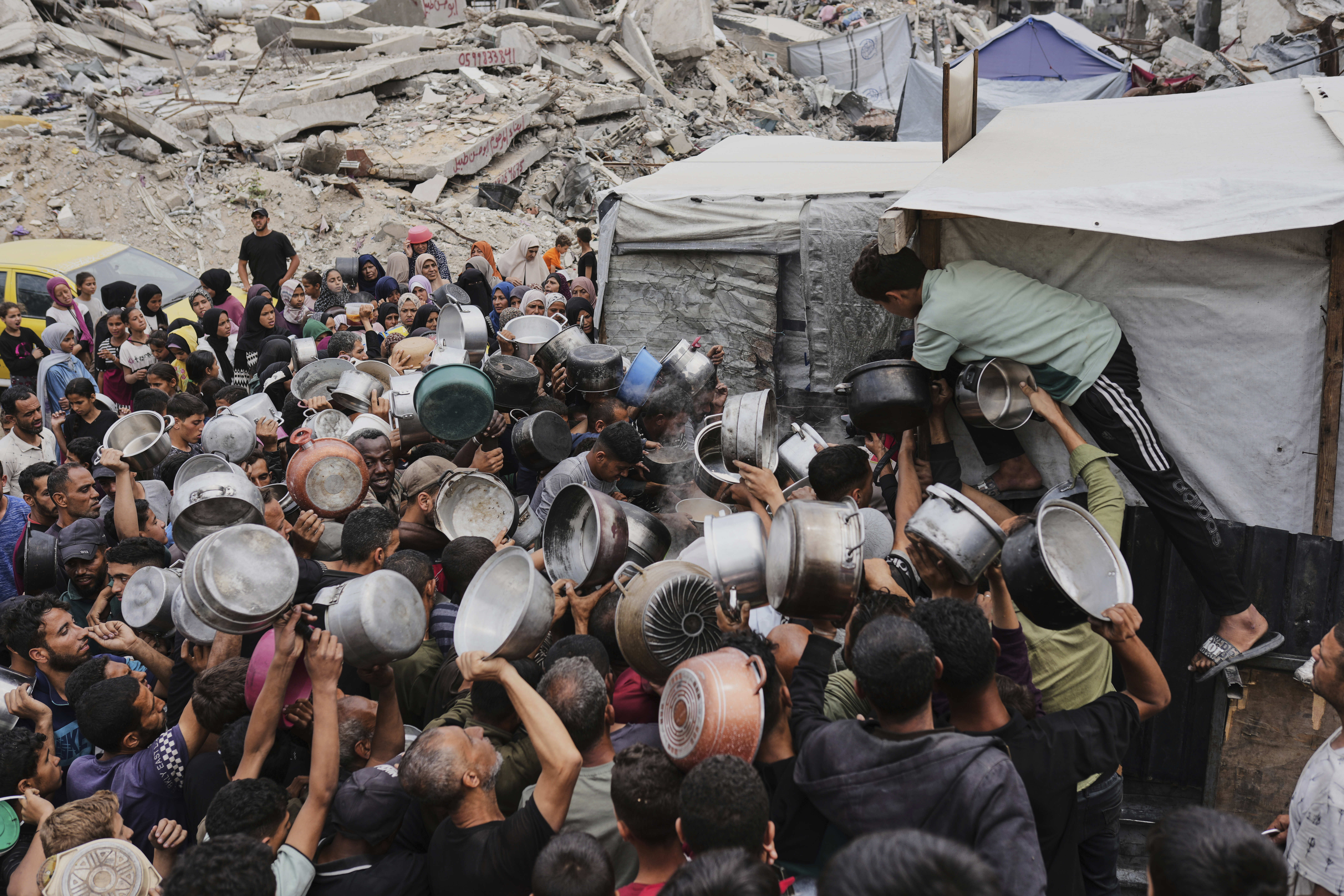 Palestinians struggle to get donated food at a community kitchen in Jabalia, northern Gaza Strip, Thursday, May 15, 2025. (AP Photo/Jehad Alshrafi)