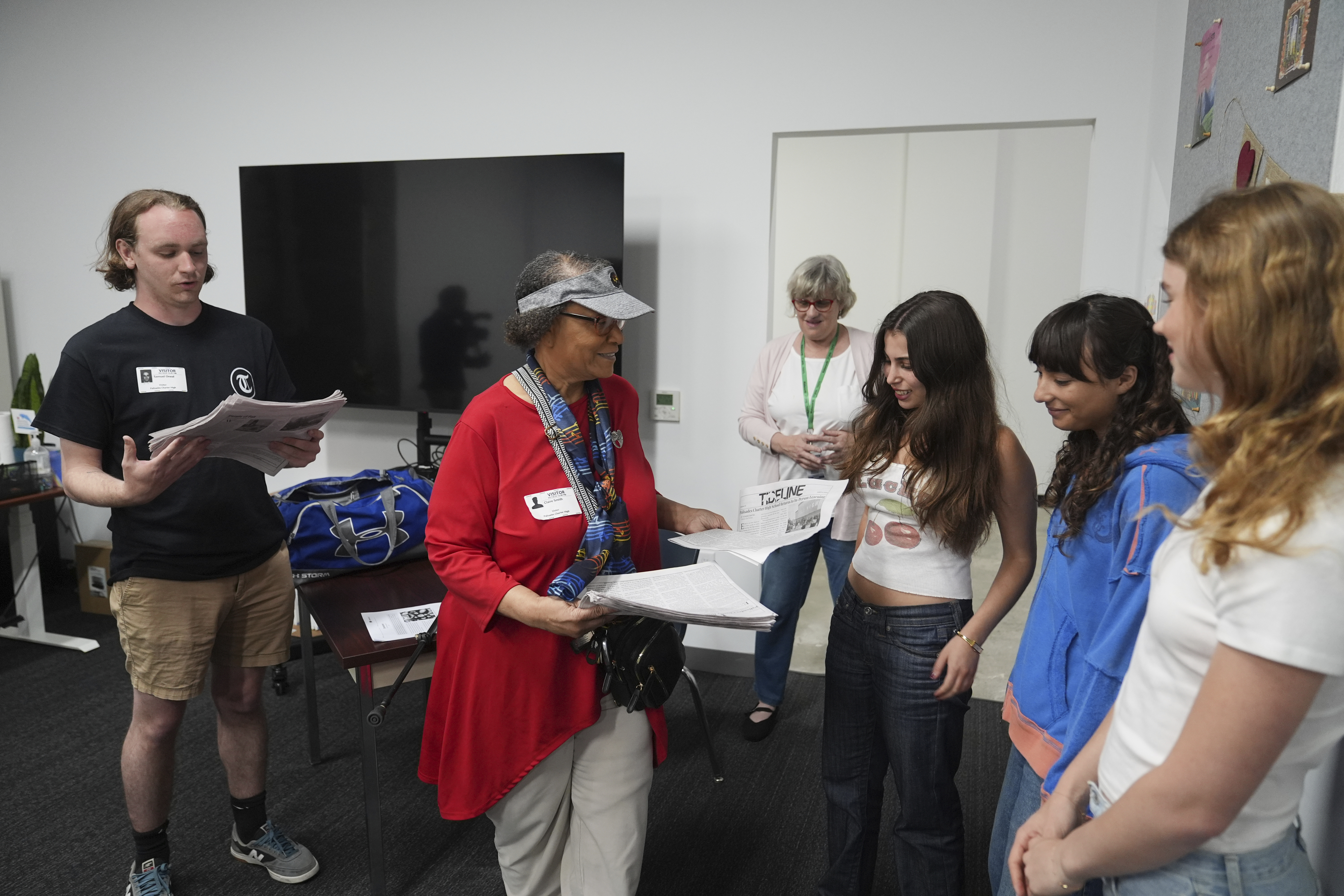 Claire Smith, founding executive director of Temple University's sports media center, center, and Samuel O'Neal, left, editor-in-chief of the Temple News, deliver copies of the Palisades High School newspaper to staff, Wednesday, May 14, 2025, in Santa Monica, Calif. (AP Photo/Marcio Jose Sanchez)