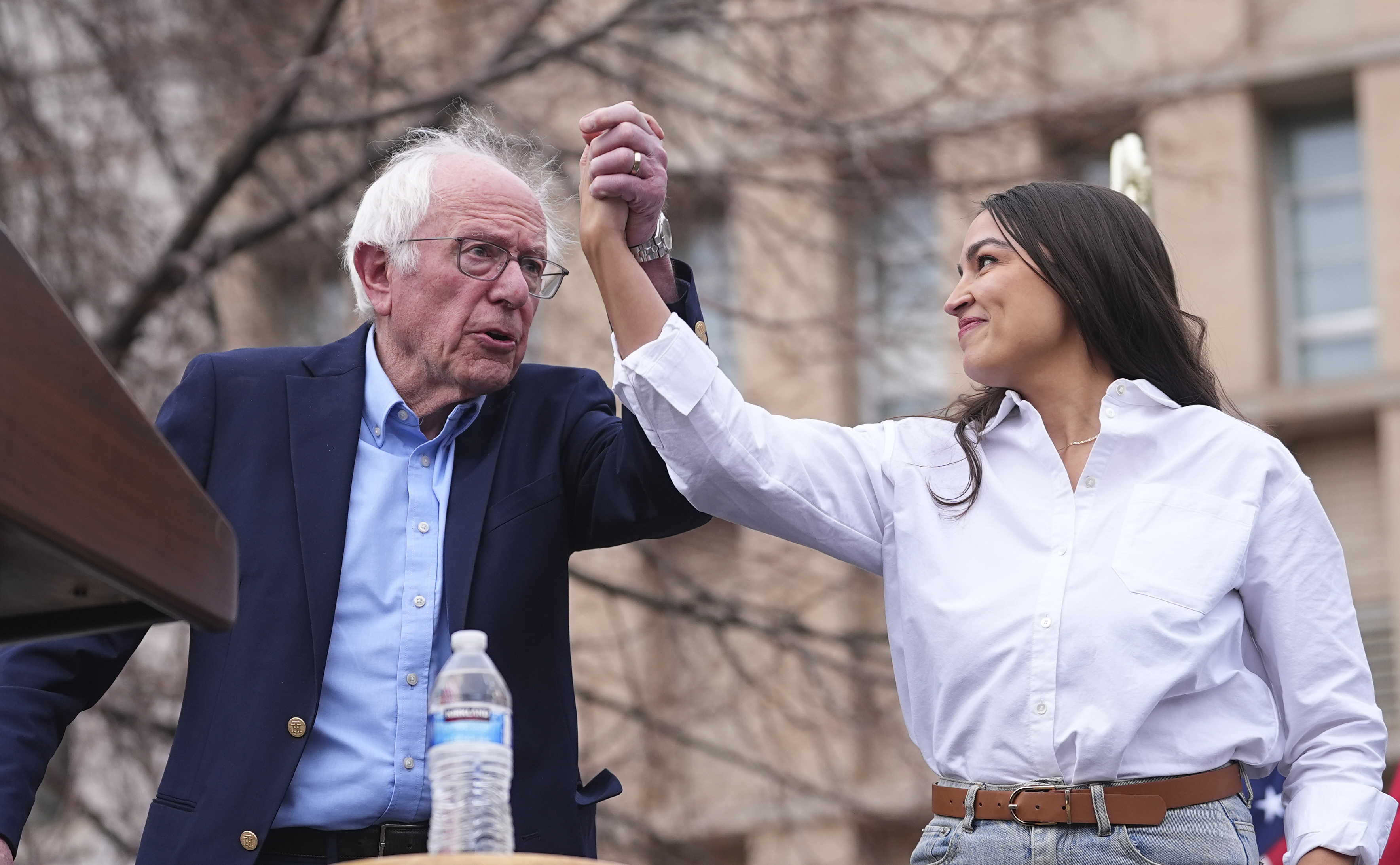 FILE _ Sen. Bernie Sanders, I-Vt., left, greets Rep. Alexandria Ocasio-Cortez, D-N.Y., as they speak during a stop of their "Fighting Oligarchy" tour at Civic Center Park, March 21, 2025, in Denver. (AP Photo/David Zalubowski, File)