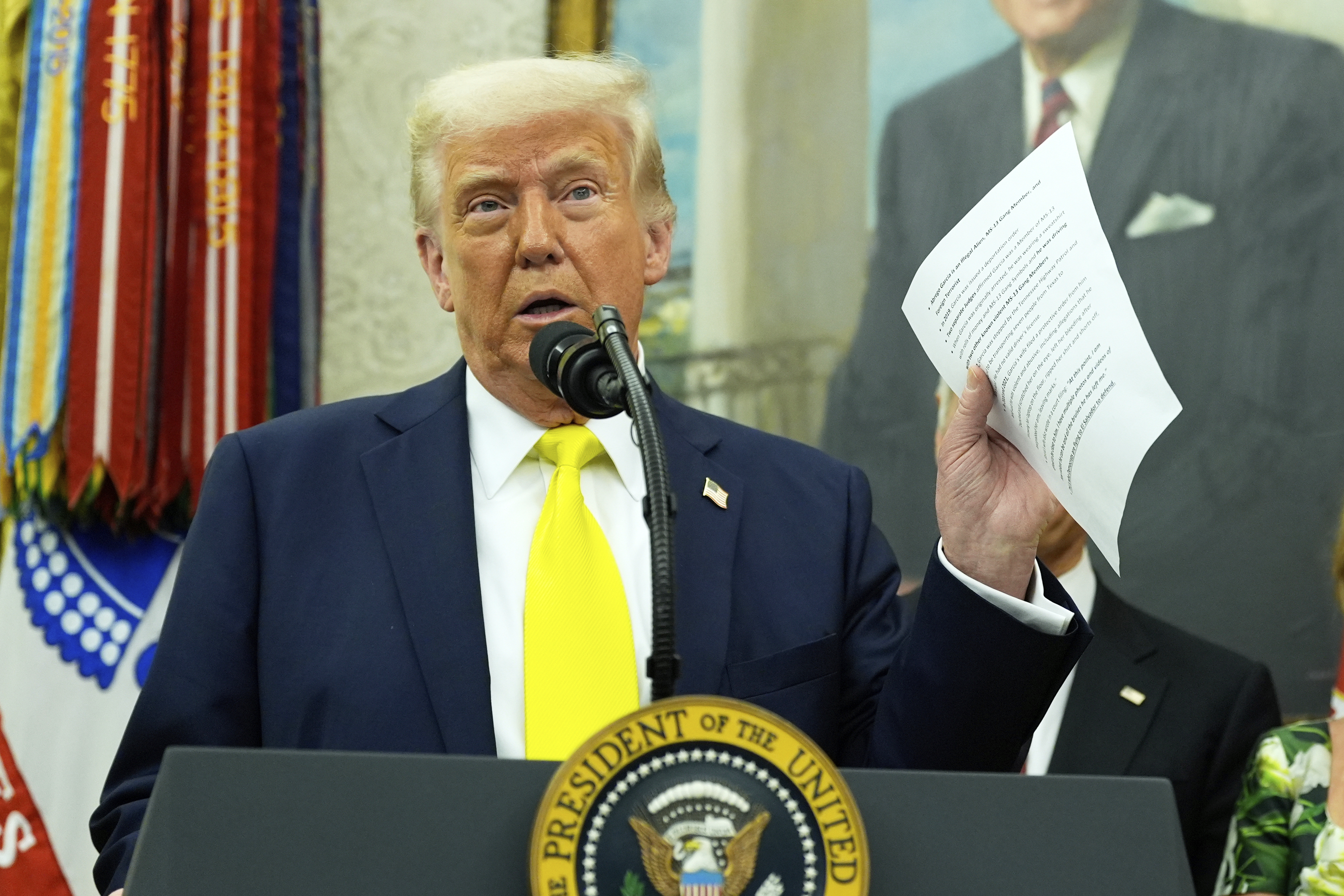 FILE - President Donald Trump holds a document with notes about Kilmar Abrego Garcia as he speaks with reporters in the Oval Office of the White House, April 18, 2025, in Washington.(AP Photo/Alex Brandon, File)