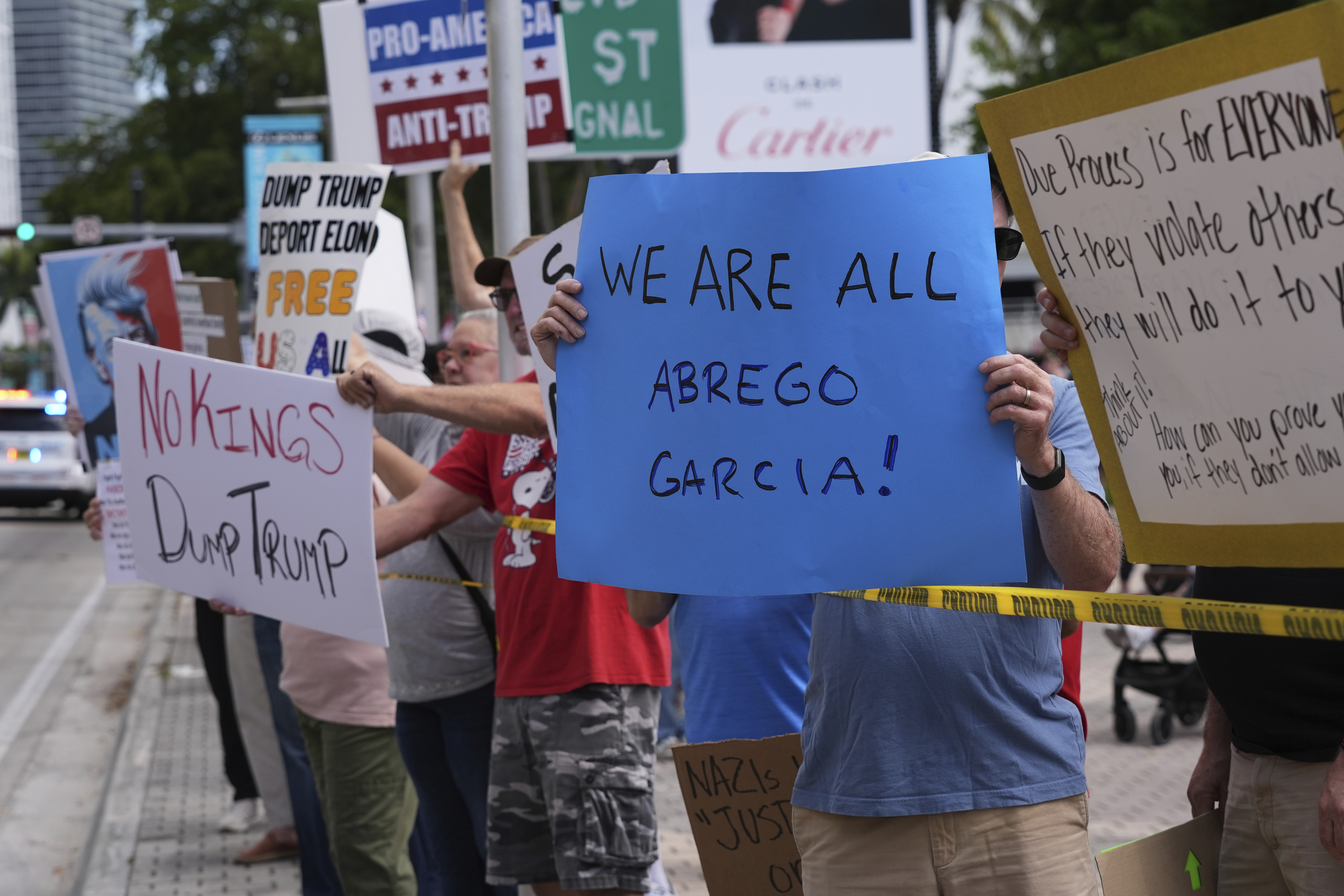 FILE - People hold signs during a protest against the Trump administration, Saturday, April 19, 2025, in Miami. (AP Photo/Lynne Sladky, File)