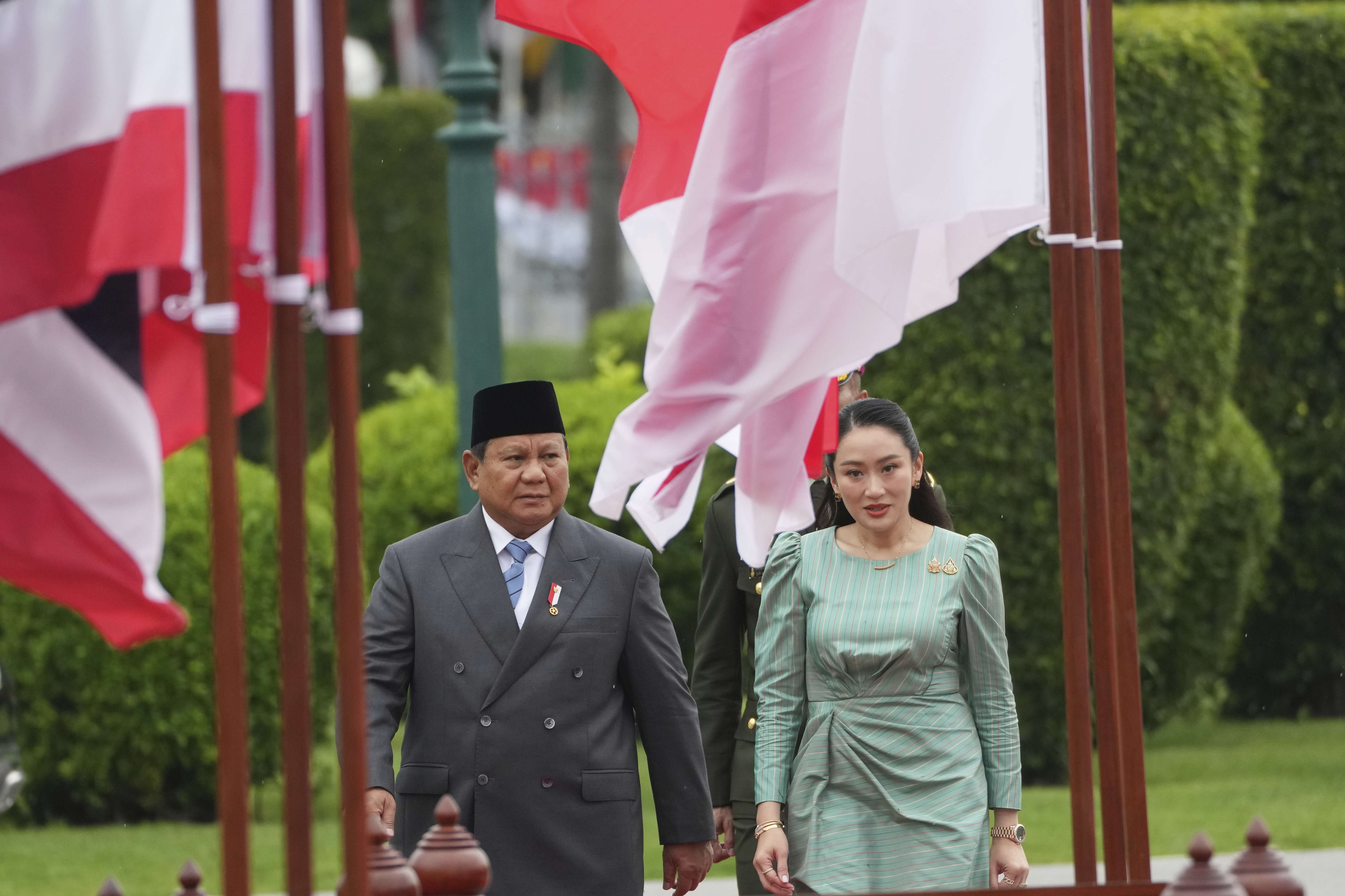 Indonesian President Prabowo Subianto, left, and Thailand's Prime Minister Paetongtarn Shinawatra arrive to review an honor guard during a welcome ceremony at the government house in Bangkok, Thailand, Monday, May 19, 2025. (AP Photo/Sakchai Lalit)
