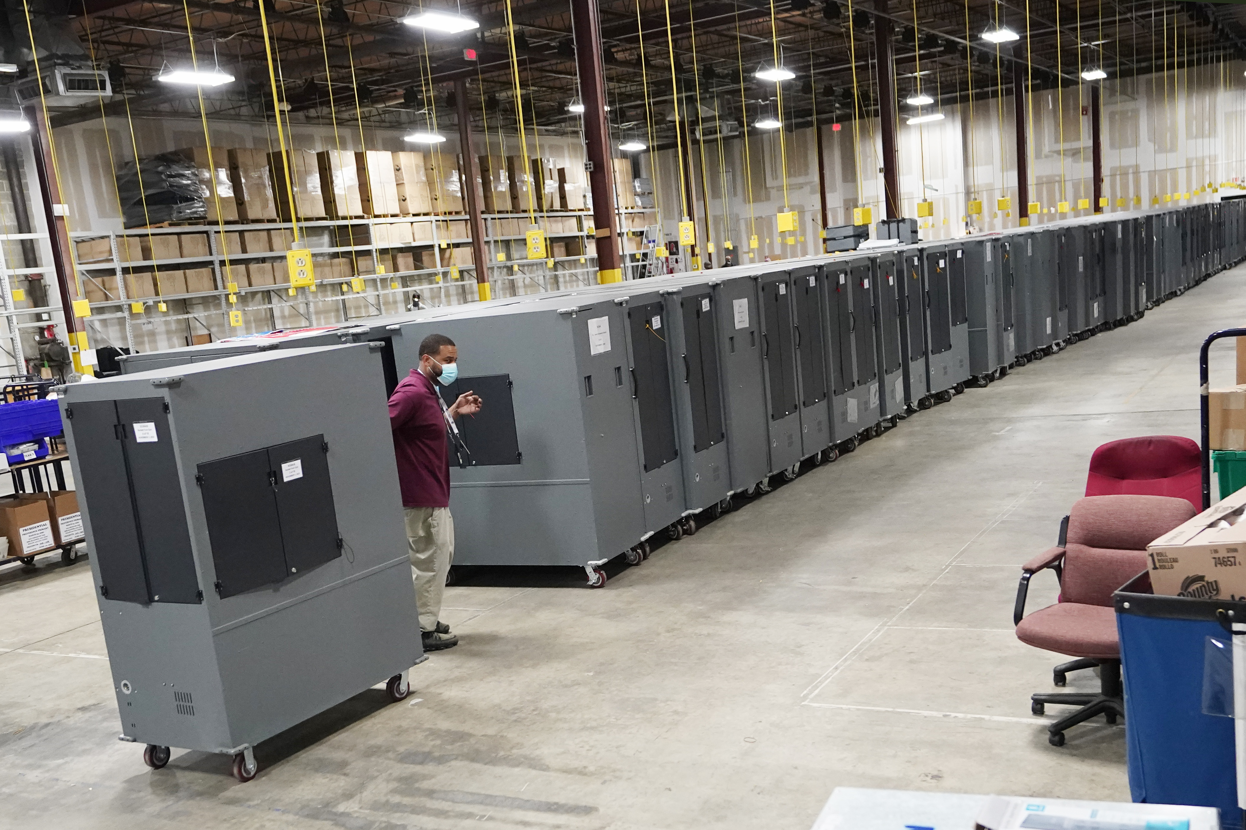 FILE - A worker returns voting machines to storage at the Fulton County Election preparation Center Nov. 4, 2020, in Atlanta. (AP Photo/John Bazemore, File)