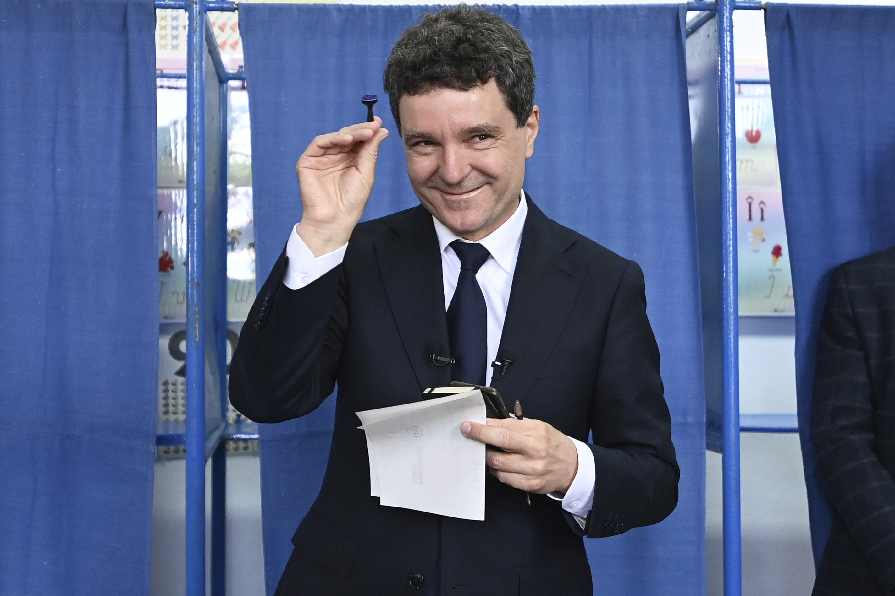 Presidential candidate Nicusor Dan smiles while holding a stamp before casting his ballot in the second round of the country's presidential election redo in Fagaras, Romania, Sunday, May 18, 2025. (AP Photo/Eduard Vinatoru)