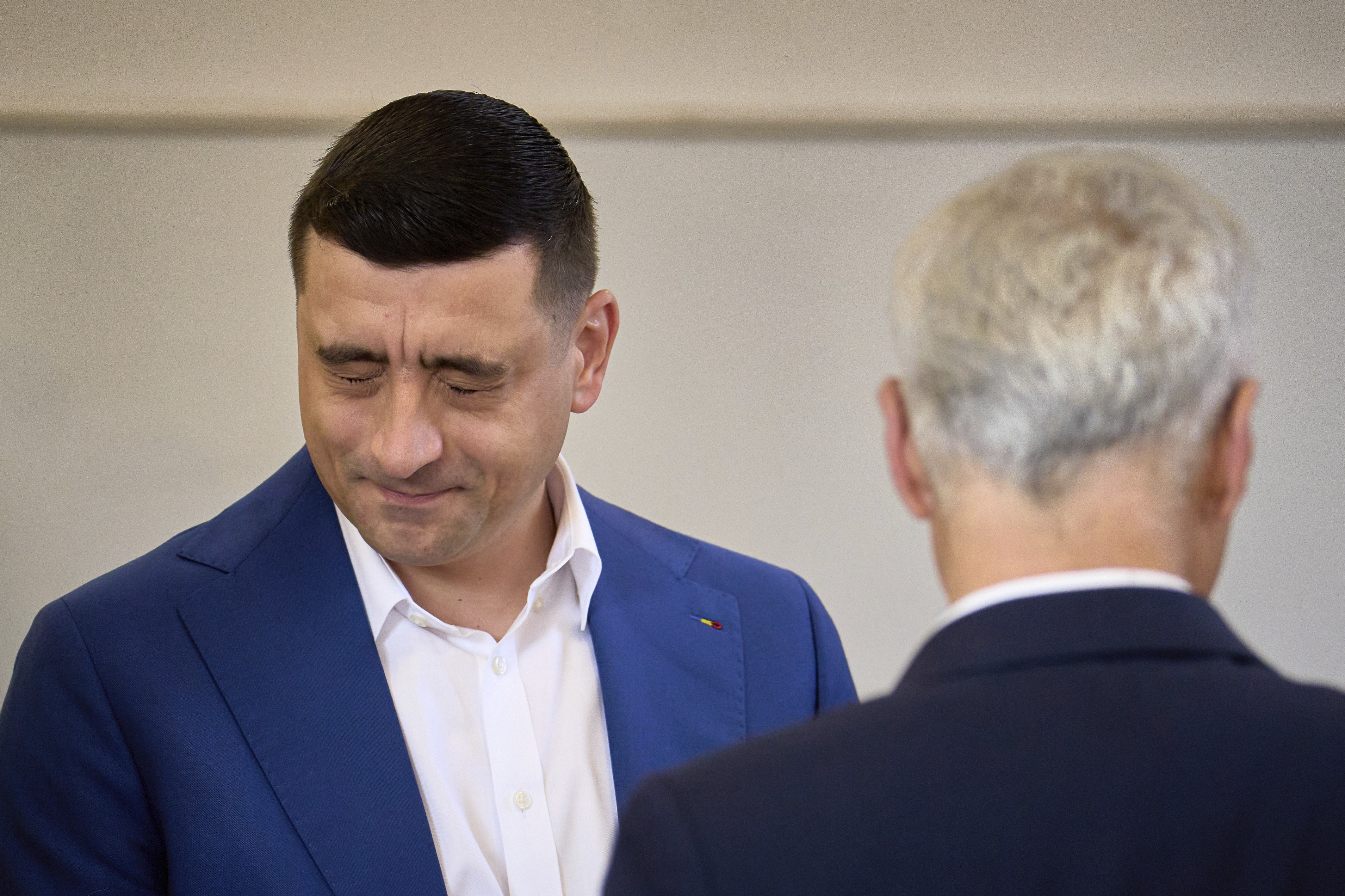 Presidential candidate George Simion grimaces next to Calin Georgescu, winner of the first round of last year's annulled election, before casting his vote in the second round of the country's presidential election redo in Mogosoaia, Romania, Sunday, May 18, 2025. (AP Photo/Vadim Ghirda)
