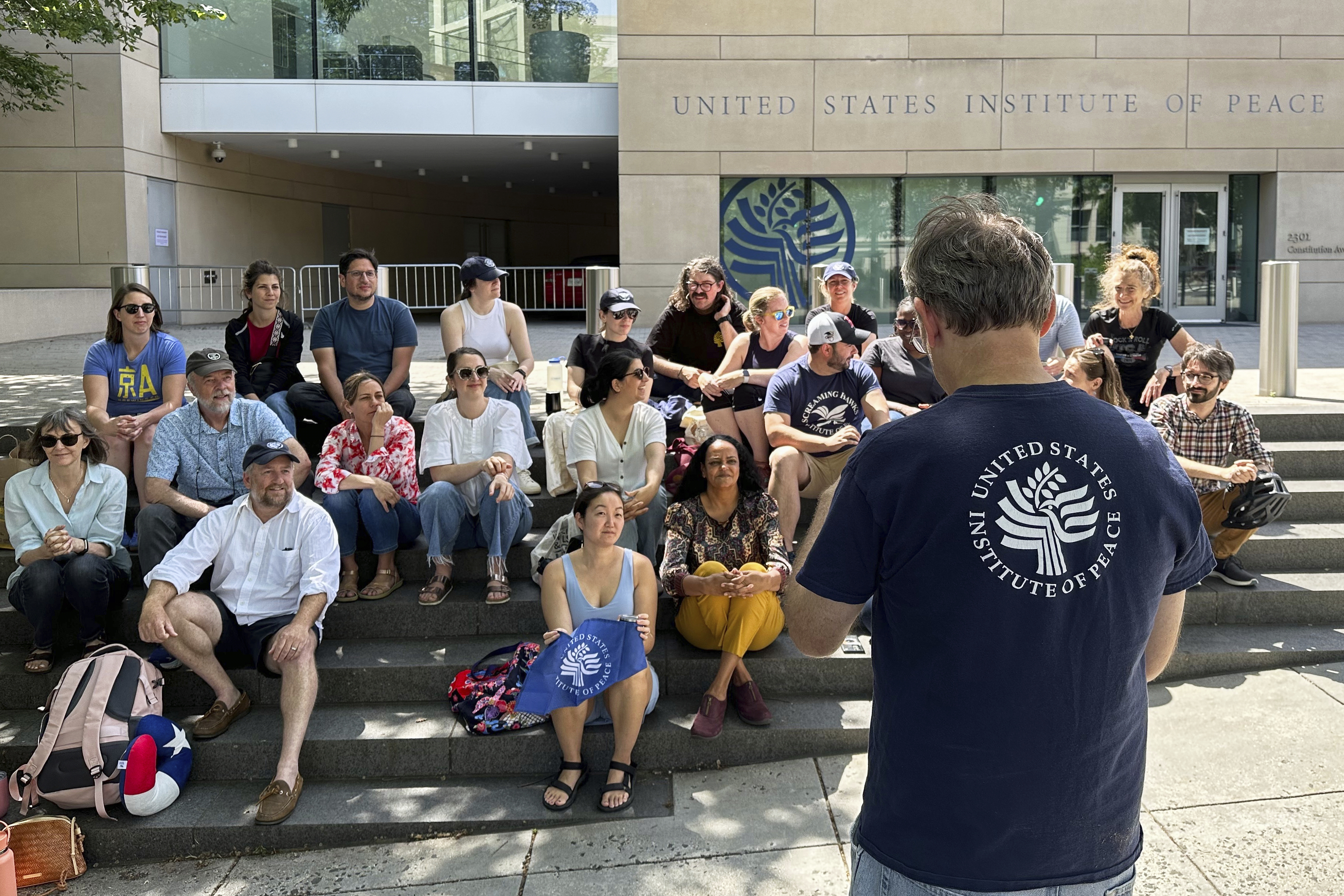 U.S. Institute of Peace employees hold an impromptu celebration on the steps of the U.S. Institute of Peace, Monday, May 19, 2025, in Washington, after federal district Judge Beryl A. Howell blocked the Trump administration from moving forward with dismantling the organization. (AP Photo/Gary Fields)