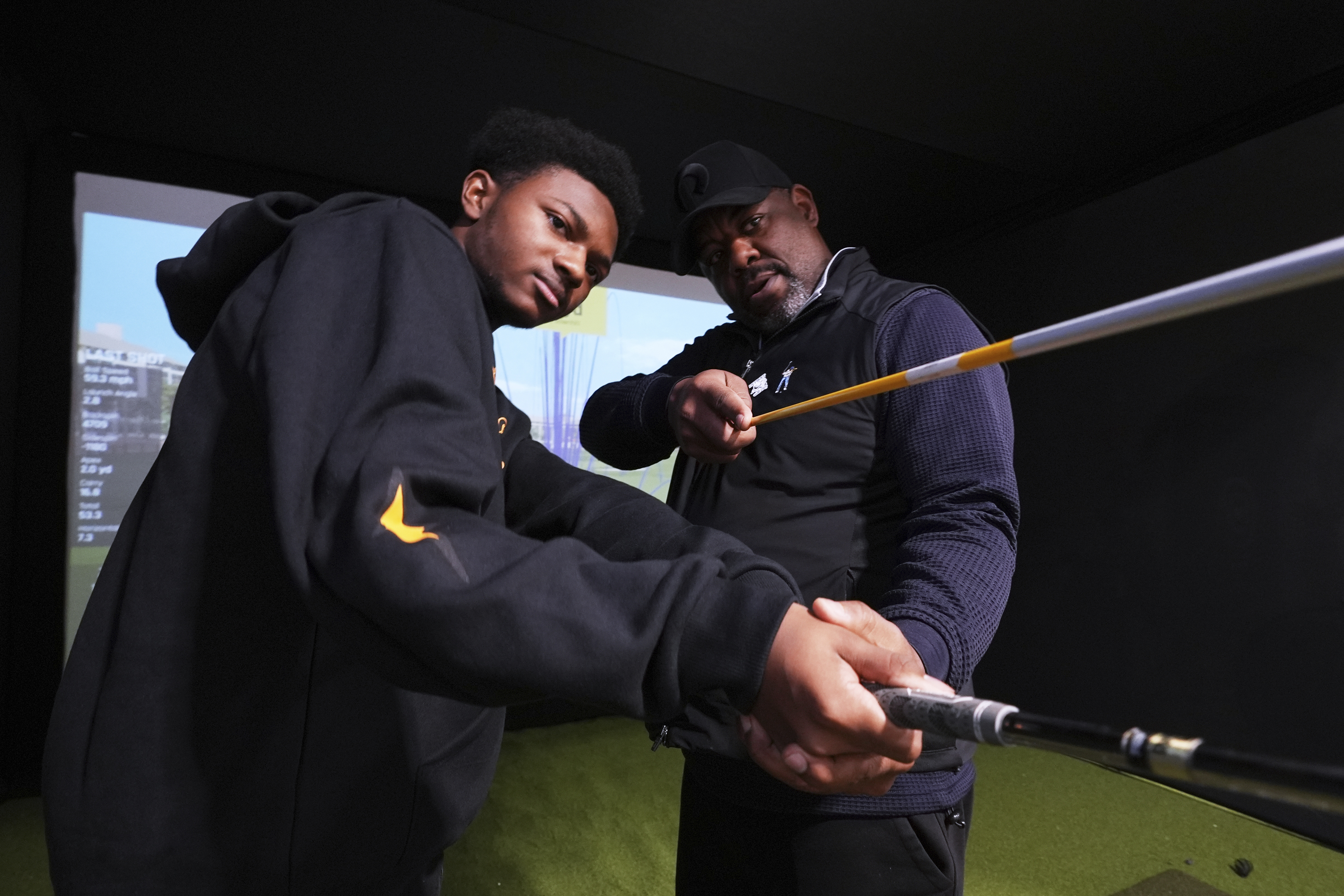 Shaun Horne, 16, a junior at Renaissance High School works on his swing with golf coach Jess Hawkins in Detroit, Thursday, Feb. 27, 2025. (AP Photo/Paul Sancya)
