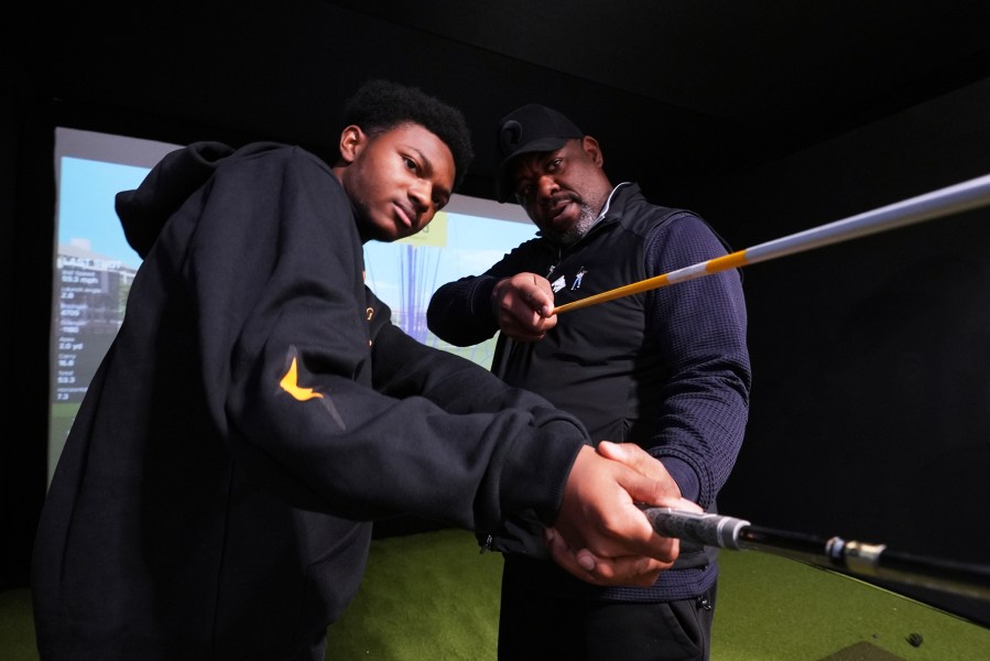 Shaun Horne, 16, a junior at Renaissance High School works on his swing with golf coach Jess Hawkins in Detroit, Thursday, Feb. 27, 2025. (AP Photo/Paul Sancya)