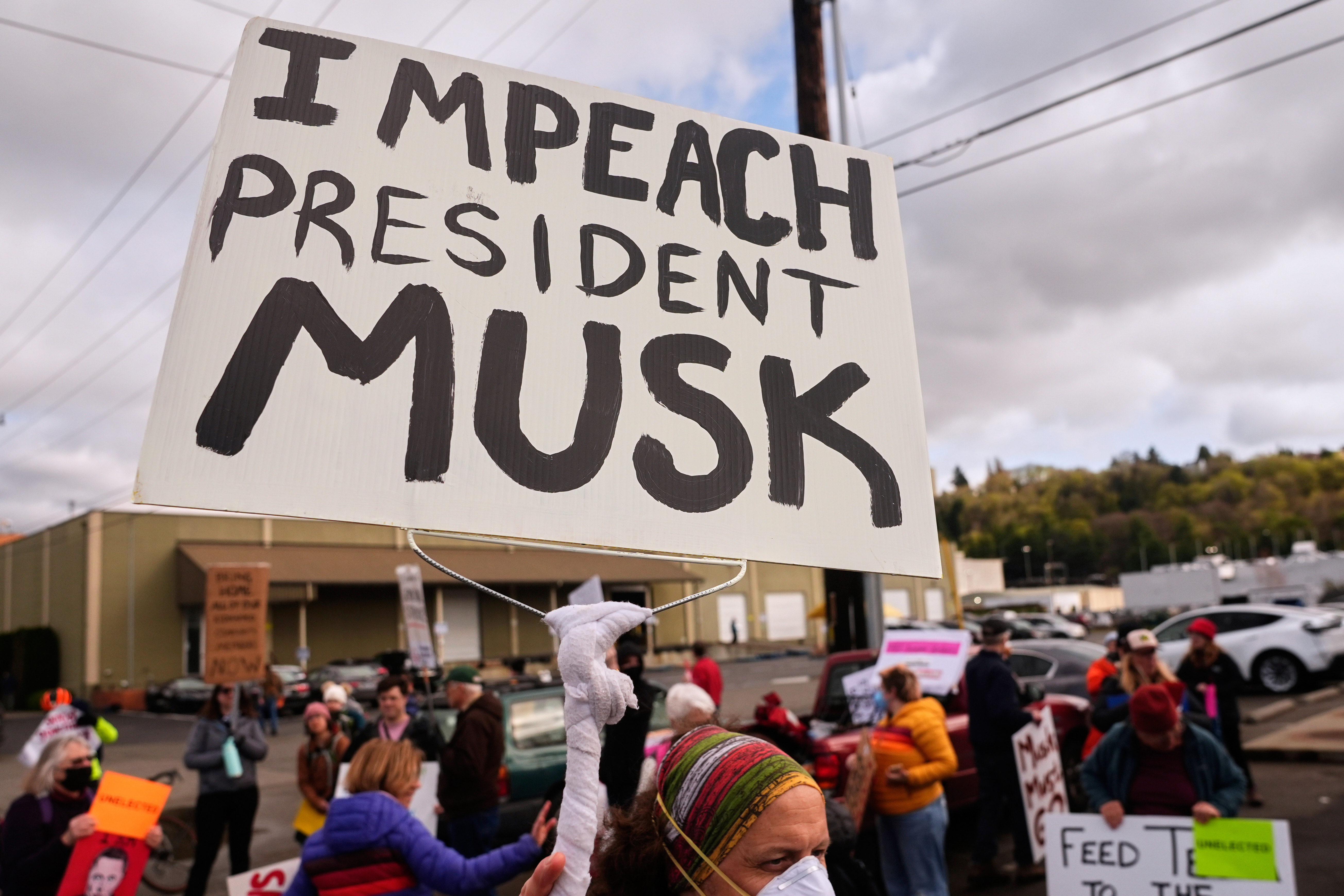 FILE - A person waves an "Impeach President Musk" sign during a protest, March 29, 2025, in Seattle. (AP Photo/Lindsey Wasson, File)