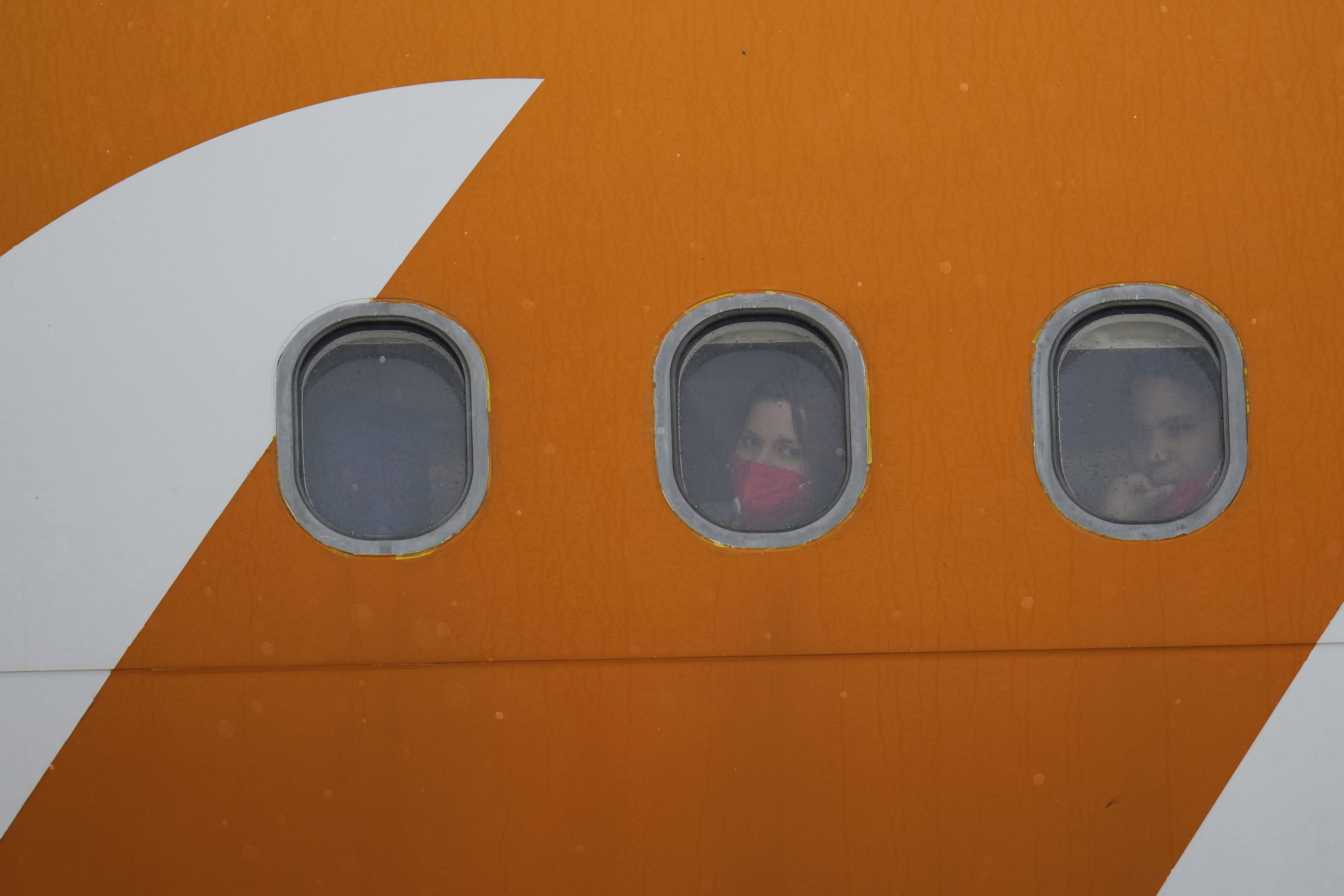Venezuelan migrants deported from the United States look out from plane portholes upon landing at the Simon Bolivar International Airport in Maiquetia, Venezuela, Friday, May 2, 2025. (AP Photo/Ariana Cubillos)