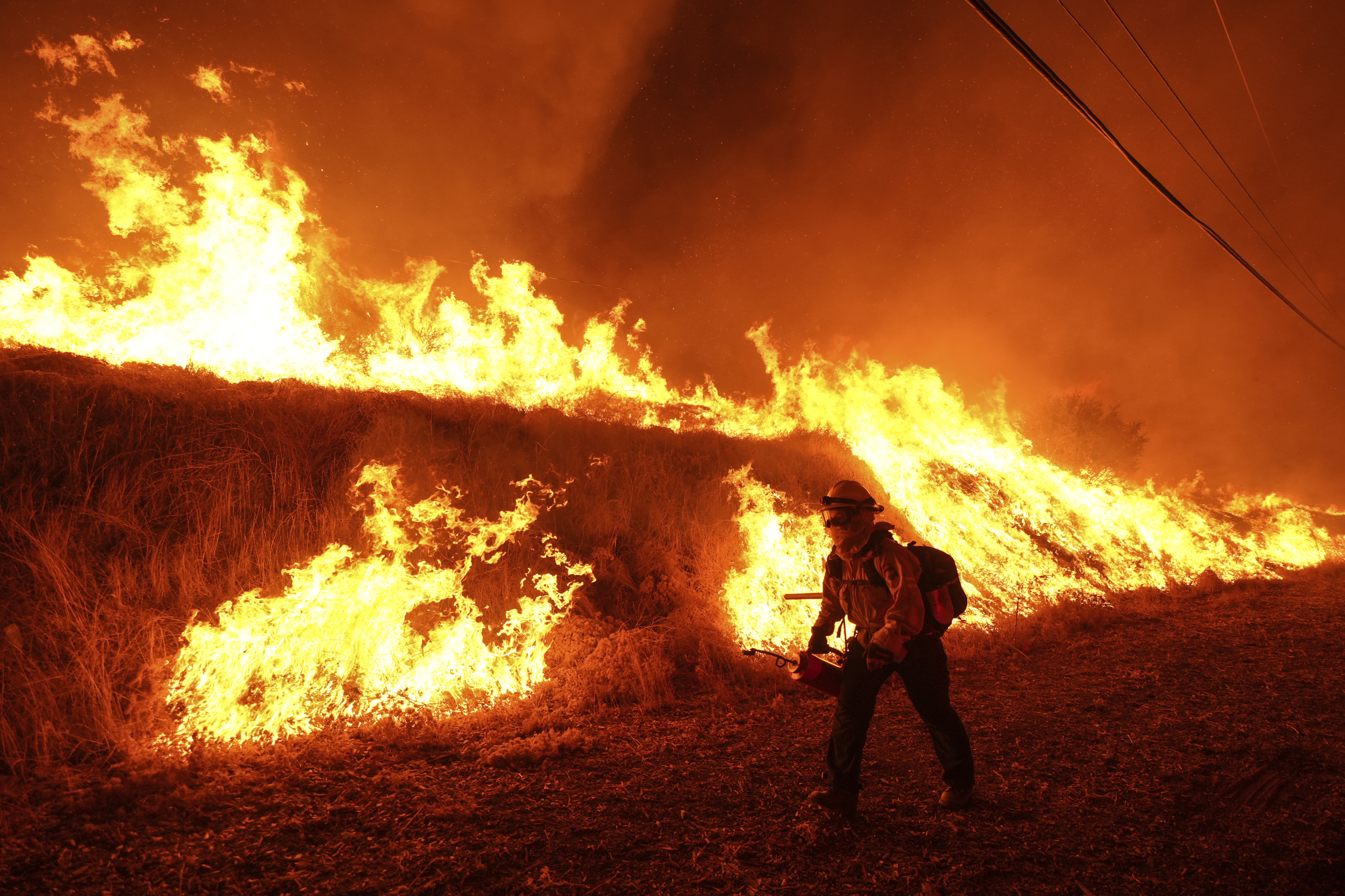 FILE - A firefighter carries a drip torch as he ignites a backfire against the Hughes Fire burning along a hillside in Castaic, Calif., Jan. 22, 2025. (AP Photo/Jae C. Hong, File)
