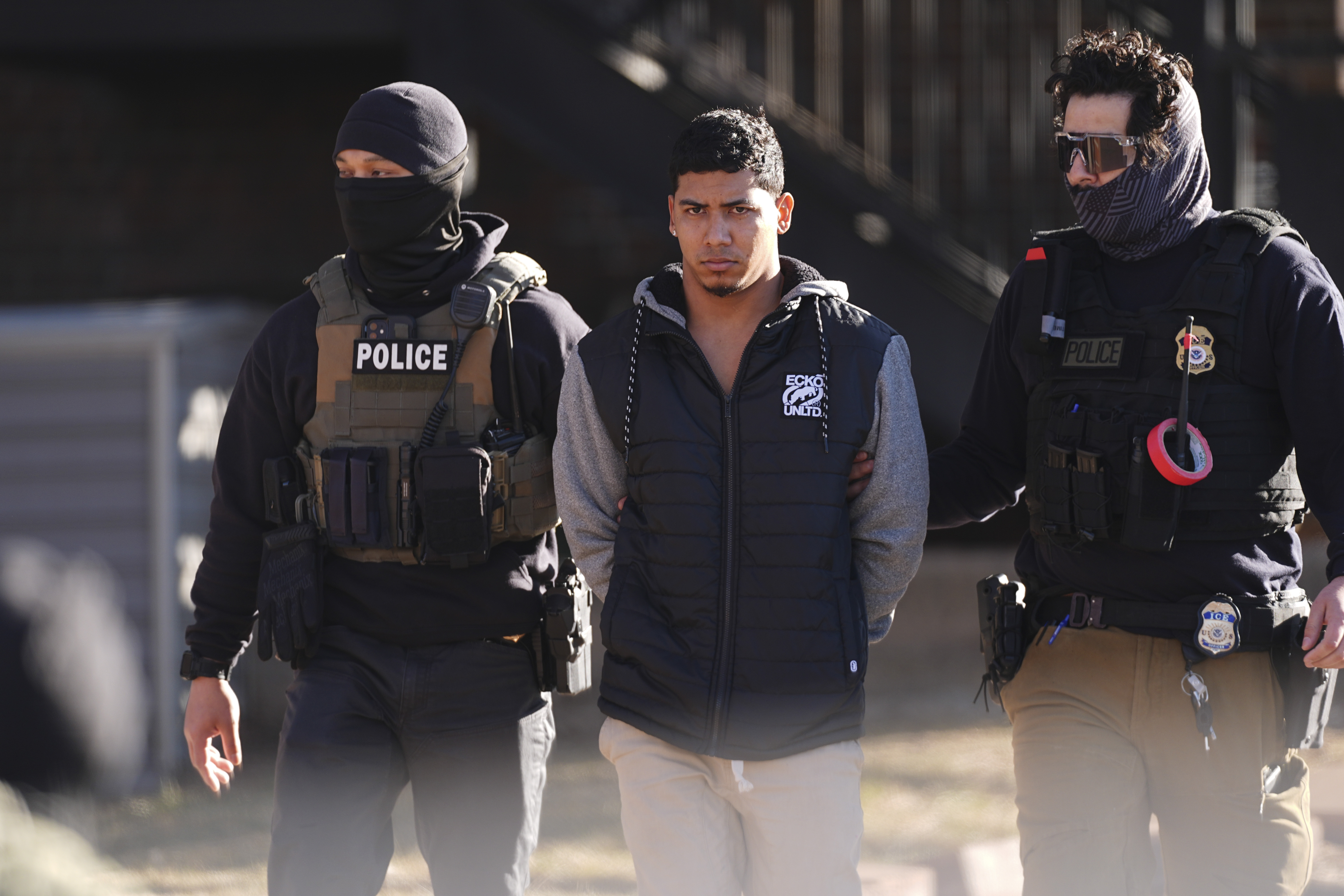 File - Law officials escort a suspect from an apartment to a waiting utility vehicle for transport during a raid Feb. 5, 2025, in east Denver. (AP Photo/David Zalubowski, File)