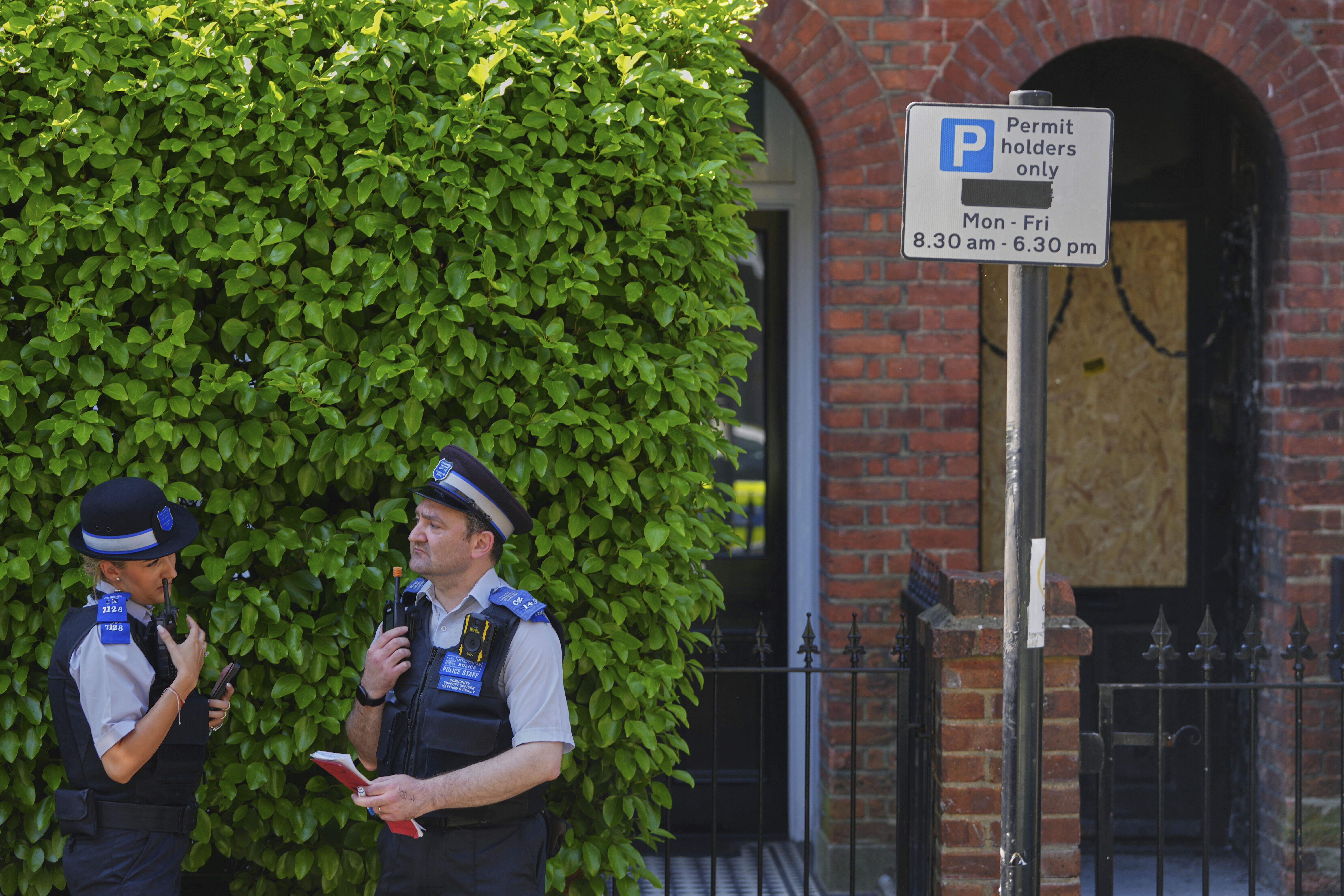 Police Community Support Officers stand near the fire damaged doorway of a house belonging to British Prime Minister Keir Starmer in Kentish Town in London, Tuesday, May 13, 2025. (AP Photo/Kirsty Wigglesworth)