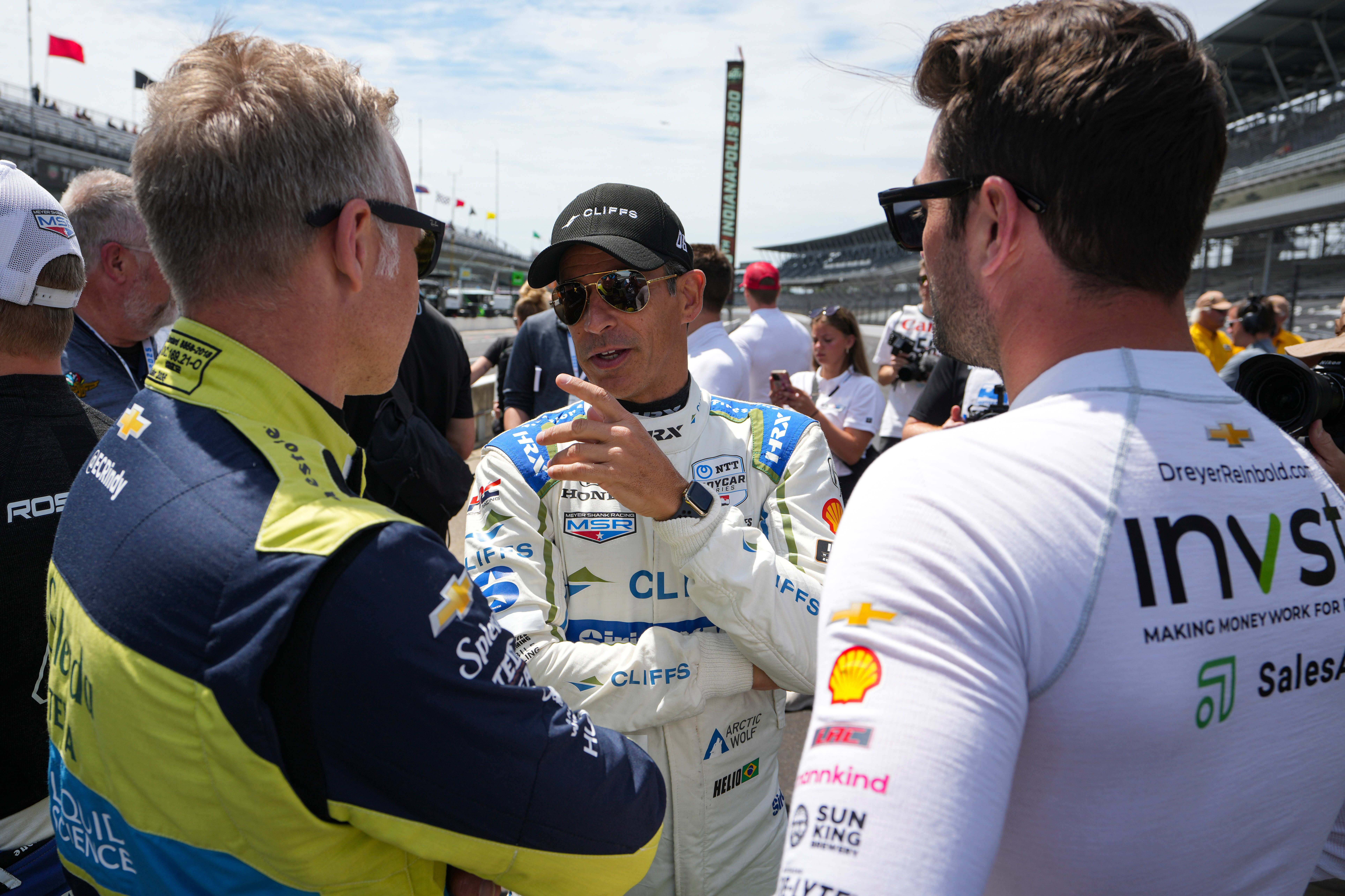 Helio Castroneves, of Brazil, center talks with Ed Carpenter, left, and Jack Harvey, of the United Kingdom, as the drivers gather for a photo before the start of practice for the Indianapolis 500 auto race at the Indianapolis Motor Speedway in Indianapolis, Monday, May 19, 2025. (AP Photo/Michael Conroy)
