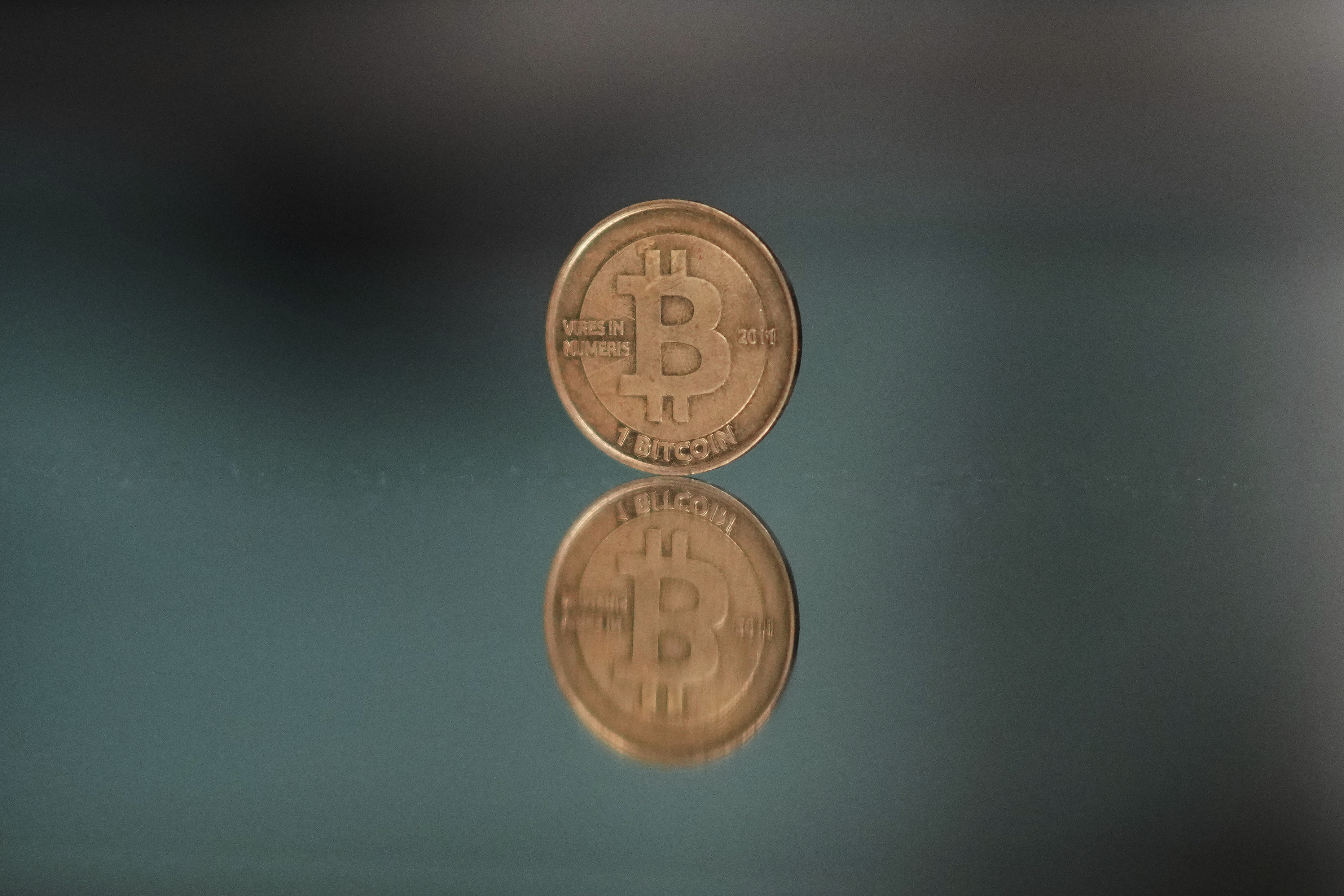 A one bitcoin token reflects as it is placed on a mirror in Prague, Czech Republic, Sunday, May 11, 2025. (AP Photo/Petr David Josek)