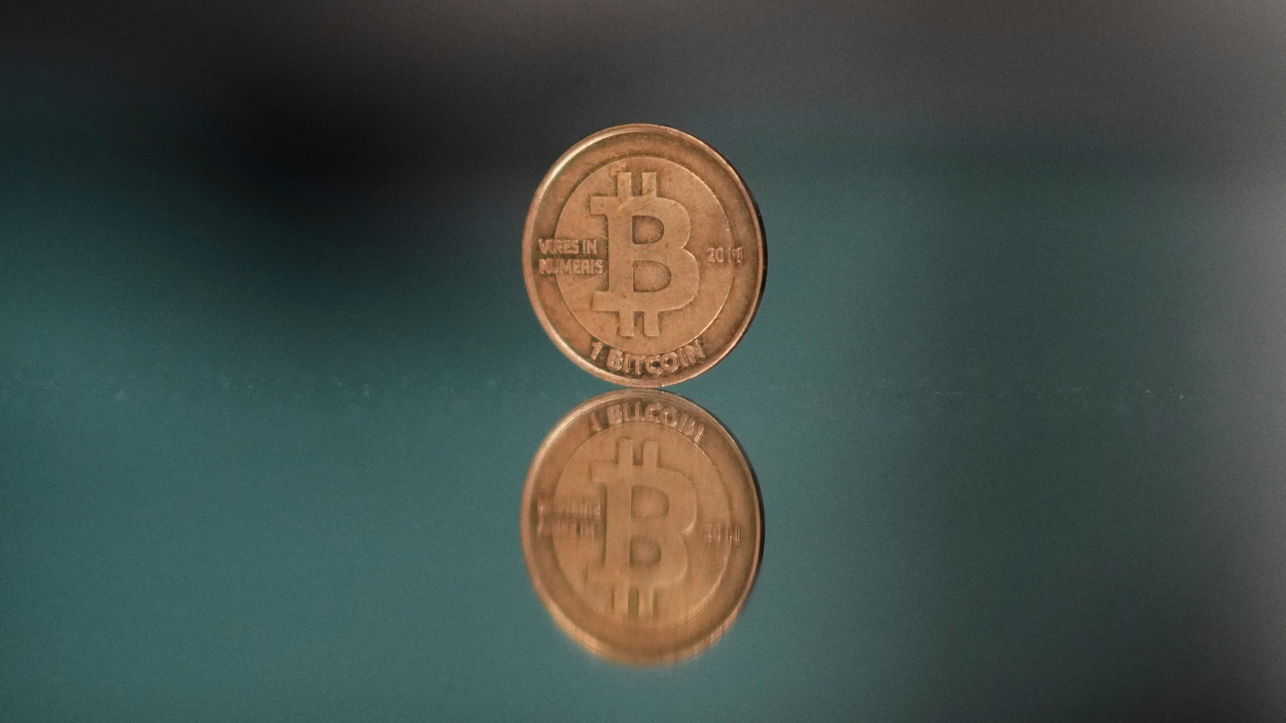 A one bitcoin token reflects as it is placed on a mirror in Prague, Czech Republic, Sunday, May 11, 2025. (AP Photo/Petr David Josek)