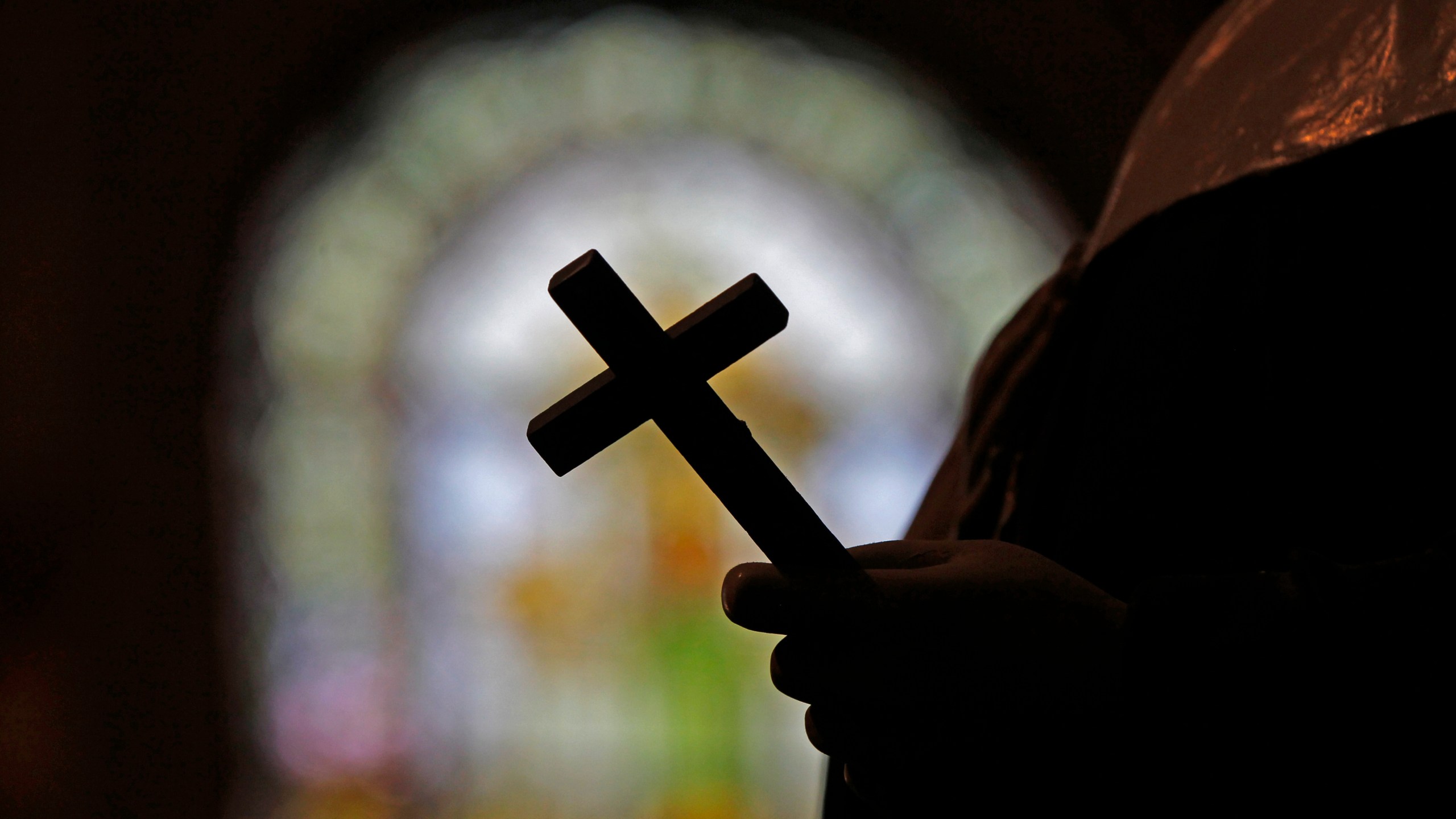 FILE - A silhouette of a crucifix and a stained glass window is seen inside a Catholic Church in New Orleans, Dec. 1, 2012. (AP Photo/Gerald Herbert, File)