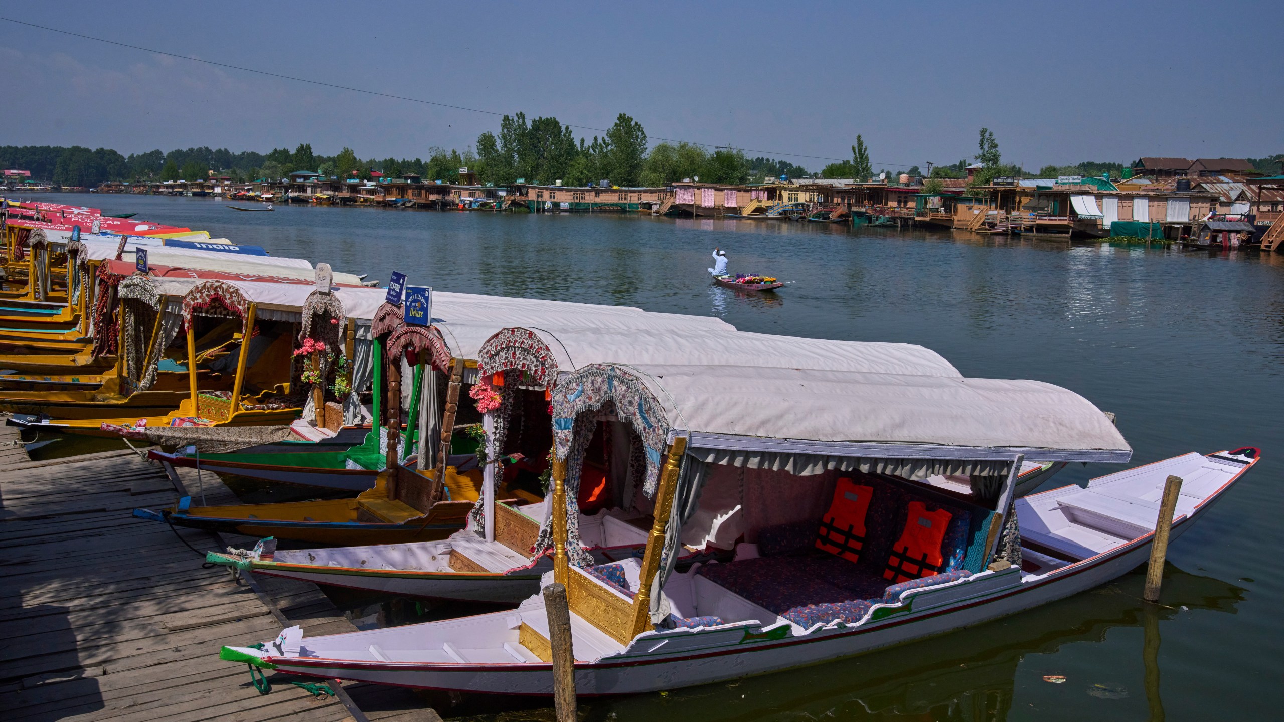 A Kashmiri flower vendor rows past anchored Shikaras, or traditional wooden boats, on Dal Lake in Srinagar, Indian controlled Kashmir, India, Tuesday, May 20, 2025. (AP Photo/Dar Yasin)