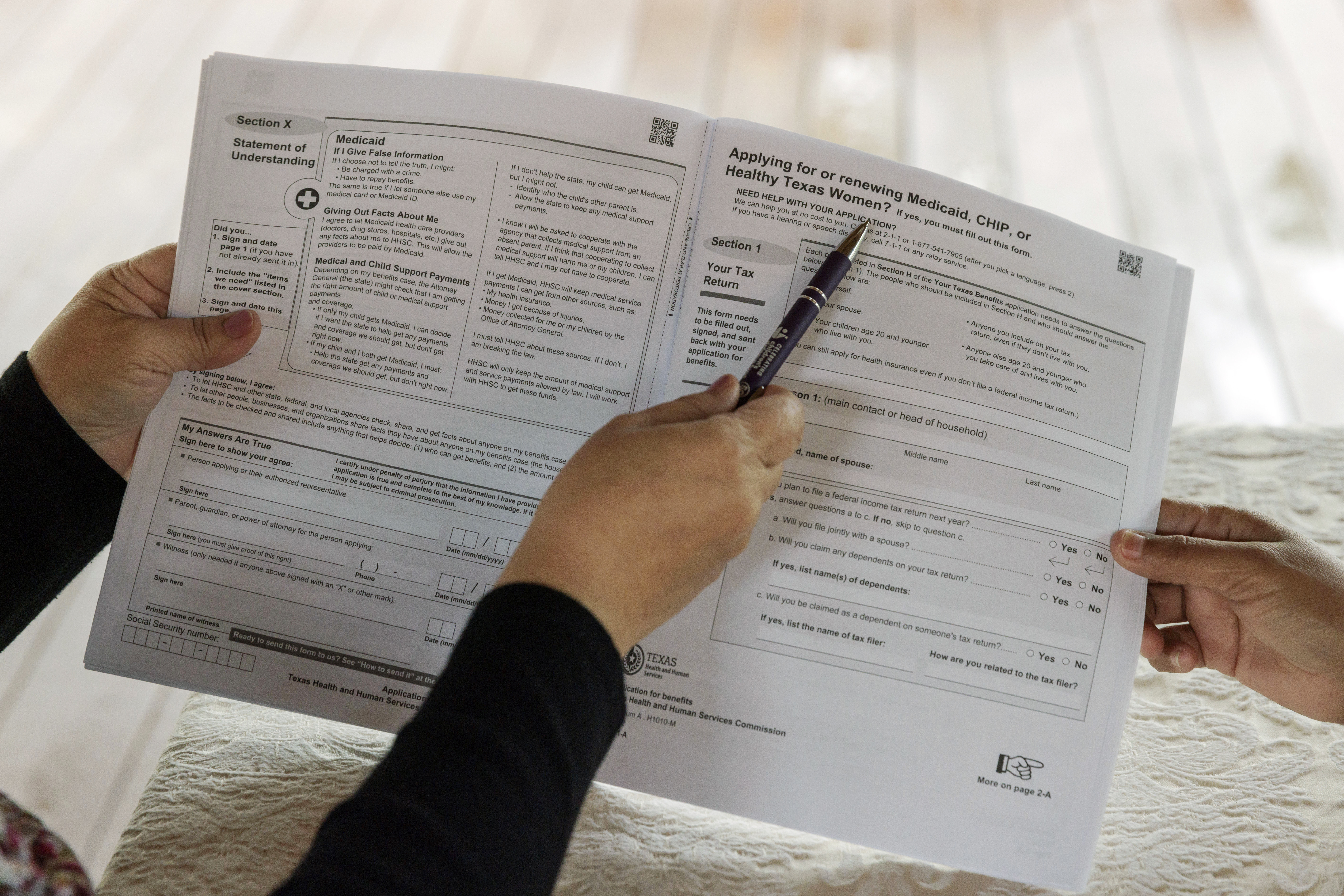 FILE - Children's Defense Fund Program Director Graciela Camarena assists Lucia Salazar with filling out Medicaid and SNAP application forms for her family in Pharr, Texas, Nov. 13, 2023. (AP Photo/Michael Gonzalez, File)