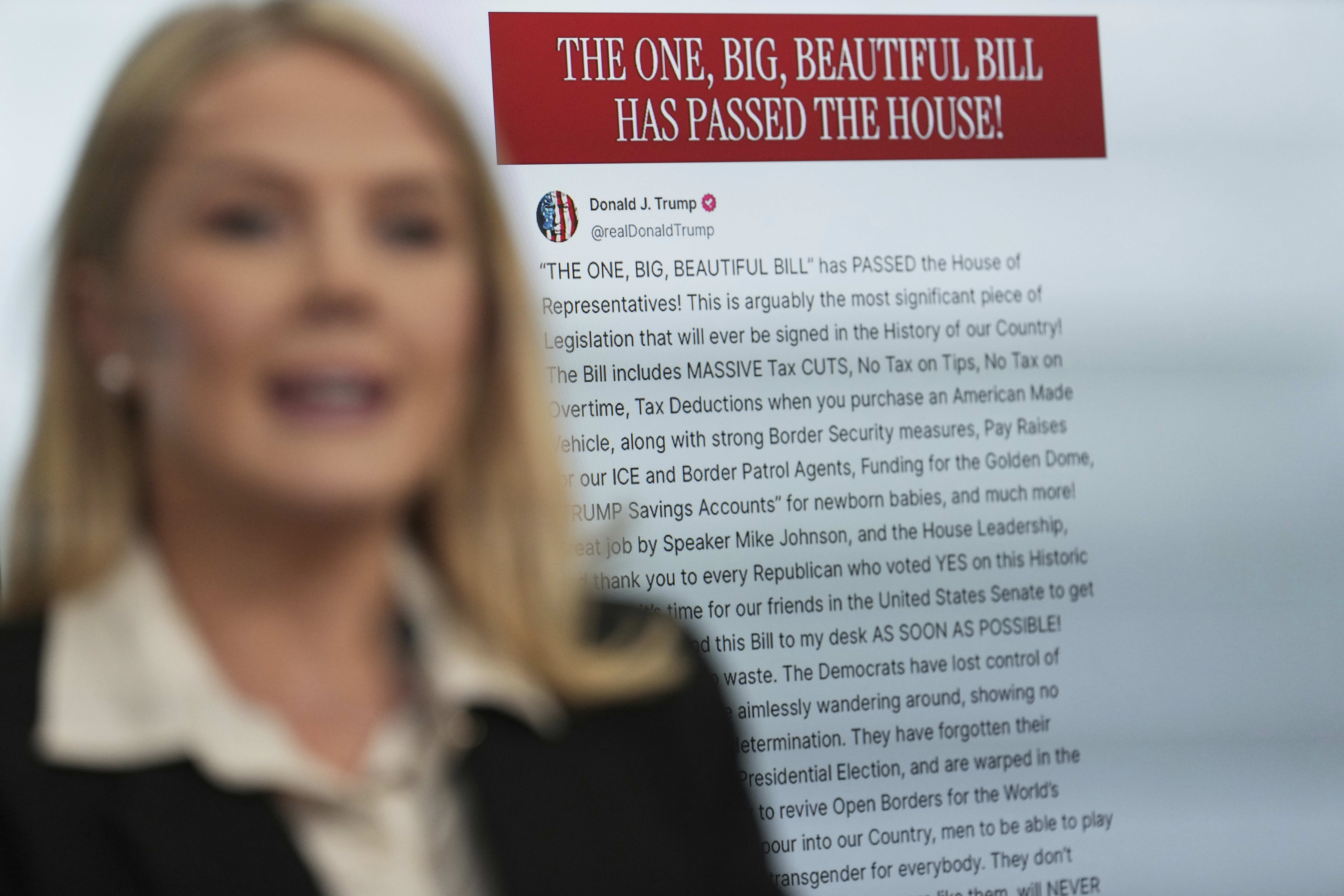 White House press secretary Karoline Leavitt speaks with reporters as an image of President Donald Trump's post on Truth Social regarding the tax cuts package appears on screen in the James Brady Press Briefing Room at the White House, Thursday, May 22, 2025, in Washington. (AP Photo/Jacquelyn Martin)