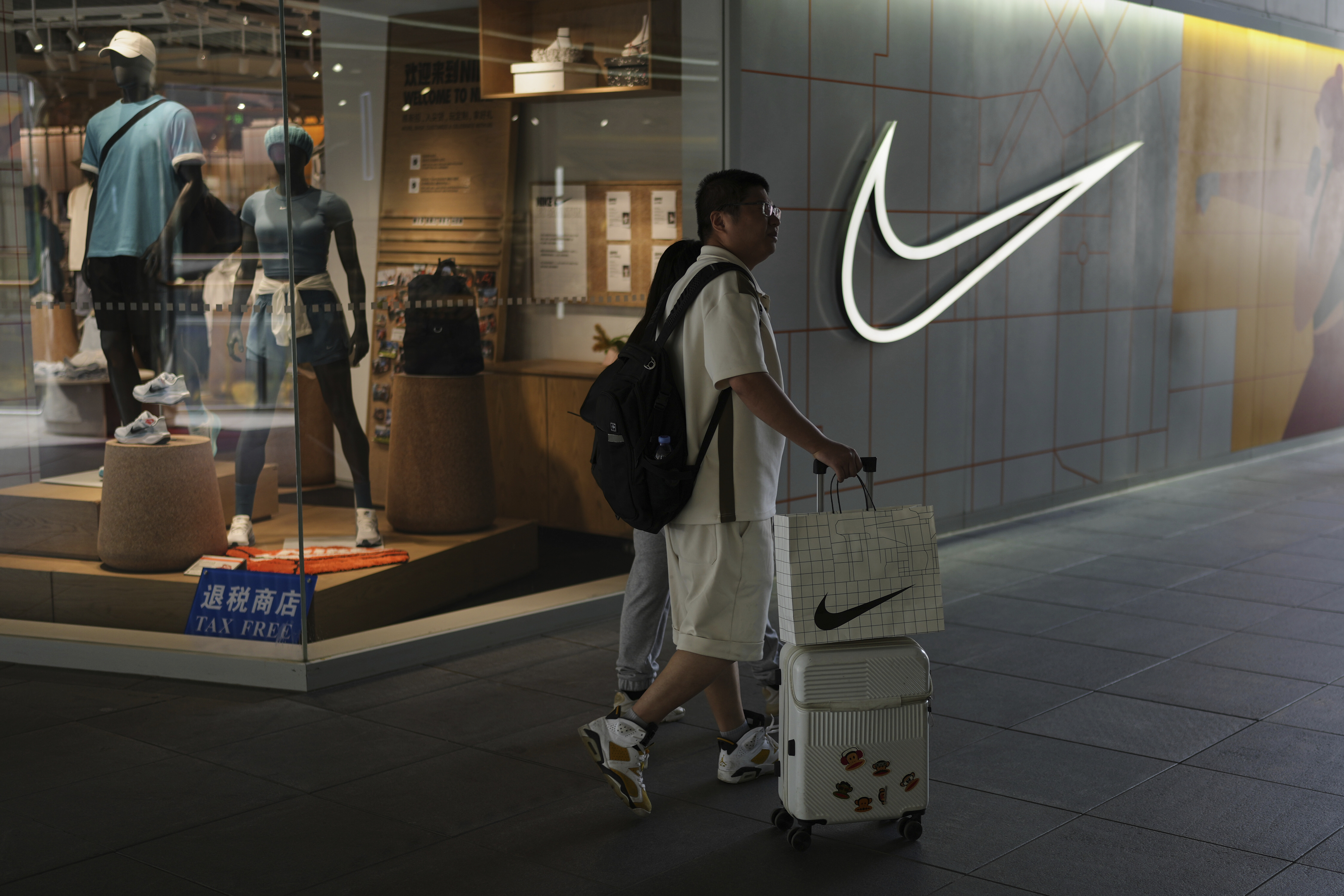 A man walks with his purchased goods as he shops at a Nike store outside a shopping mall in Beijing, Sunday, May 11, 2025. (AP Photo/Andy Wong)