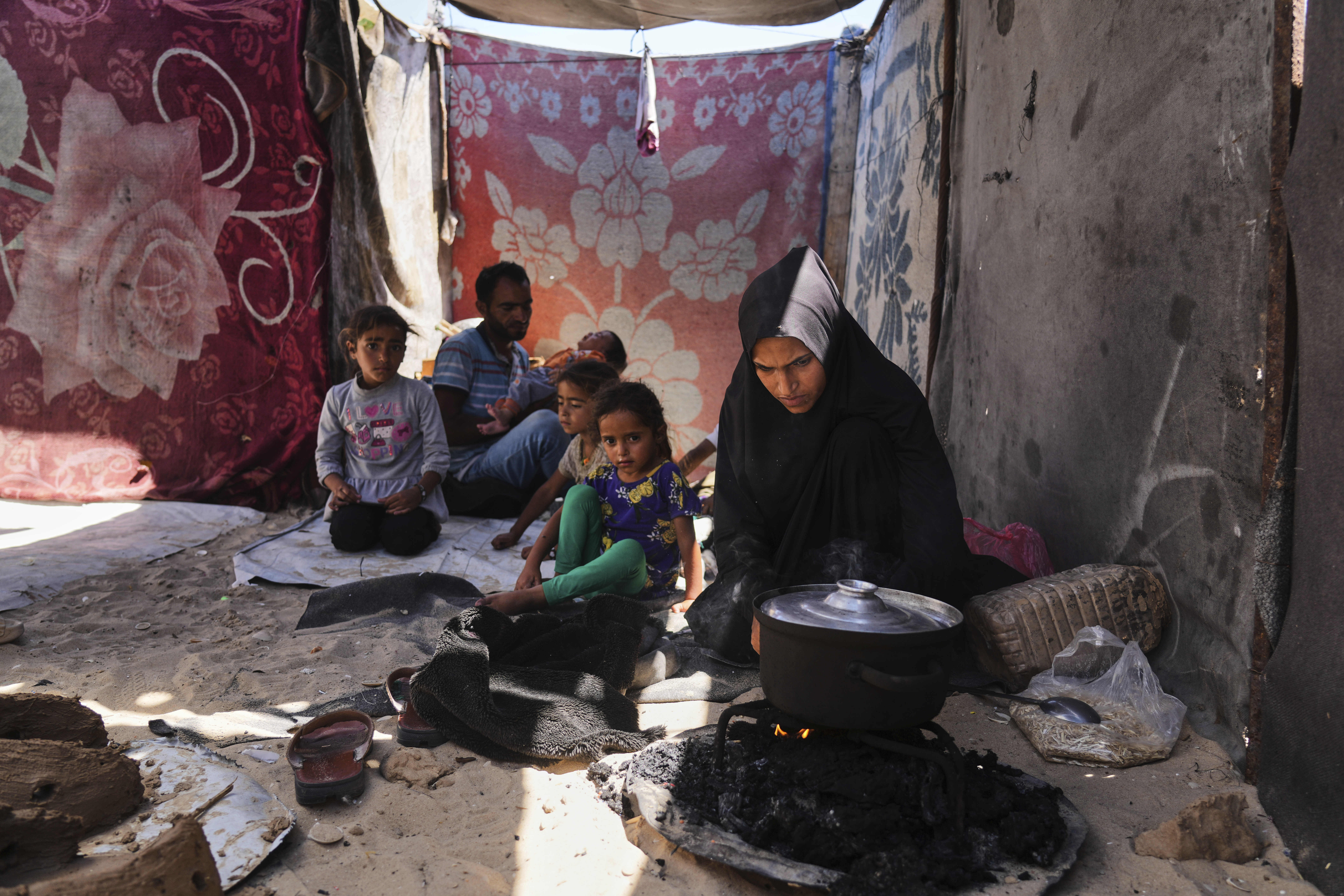 Nouf Al-Arja, 30, who suffers from malnutrition, cooks for her family inside their tent in a camp for displaced Palestinians in Muwasi, Khan Younis, Gaza, Wednesday, May 21, 2025. (AP Photo/Abdel Kareem Hana)
