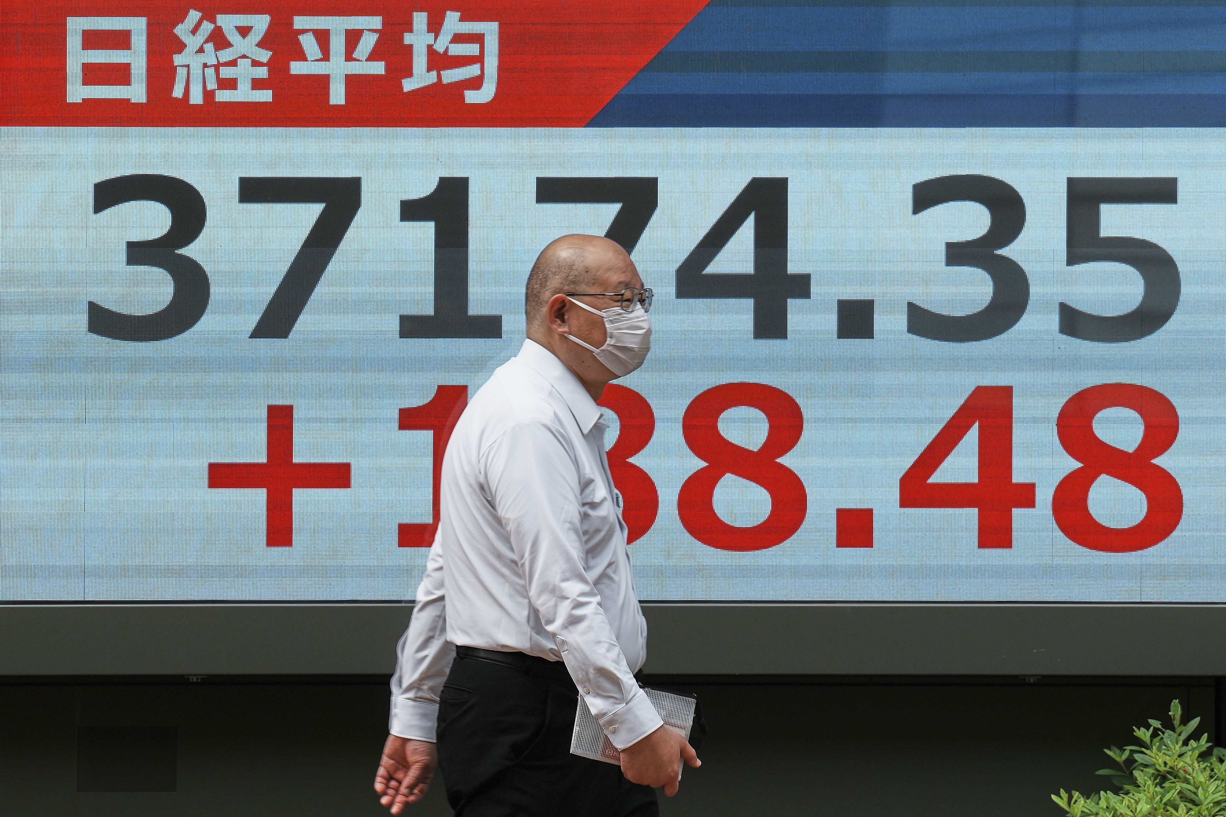 A person walks in front of an electronic stock board showing Japan's Nikkei index at a securities firm Friday, May 23, 2025, in Tokyo. (AP Photo/Eugene Hoshiko)