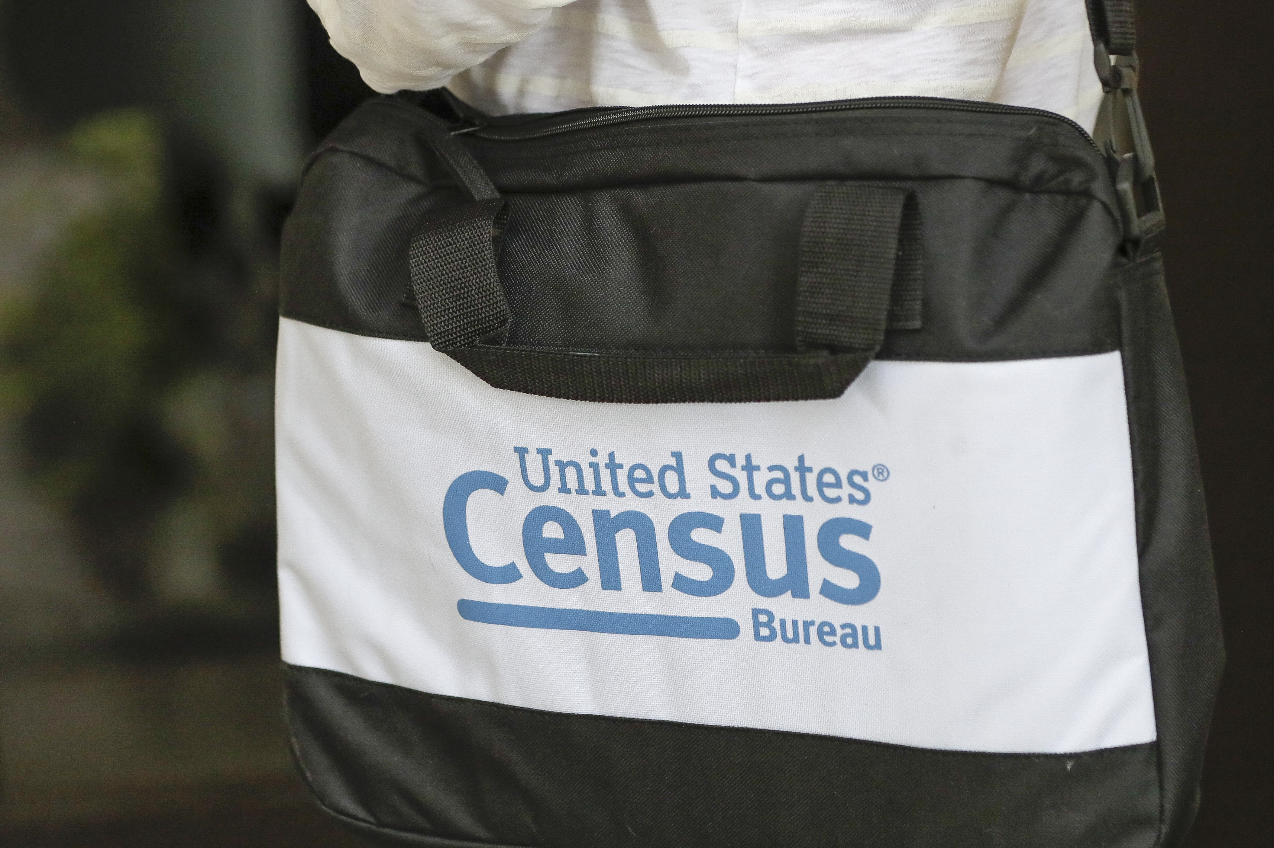 FILE - A census taker carries a briefcase as she knocks on the door of a residence in Winter Park, Fla., Aug. 11, 2020. (AP Photo/John Raoux, File)